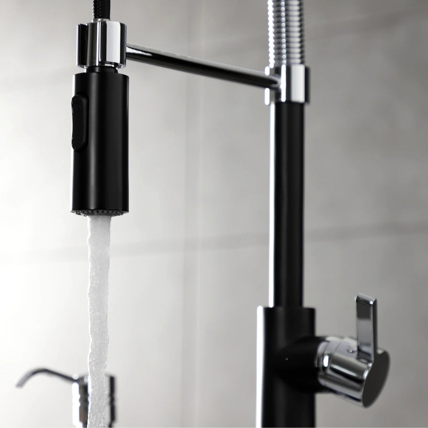 Matte black kitchen faucet with chrome spray head, flexible hose, and water stream