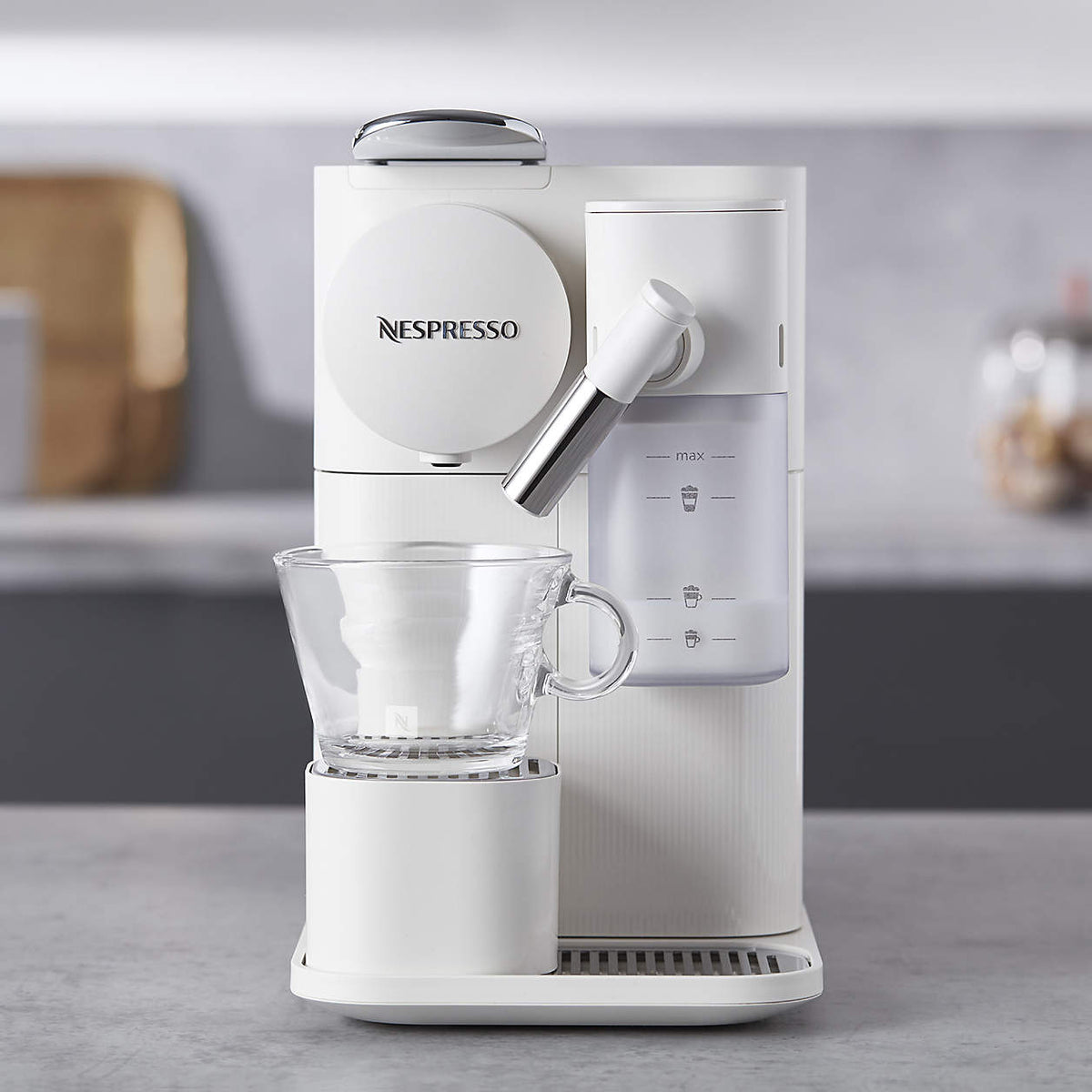 White coffee machine with spout and clear cup on lower platform, milk frothing