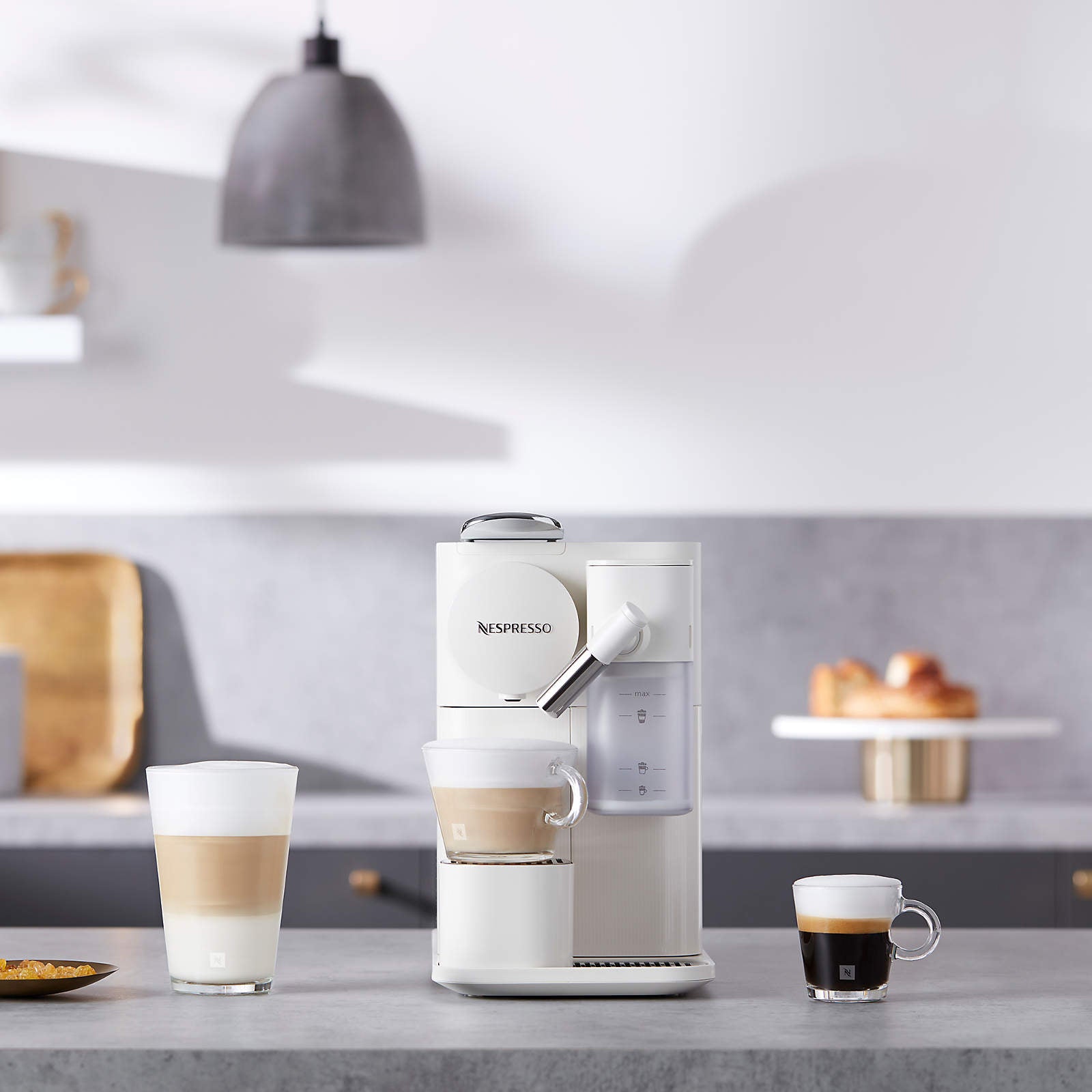 White single-serve coffee machine with frother spout, serving cups on counter
