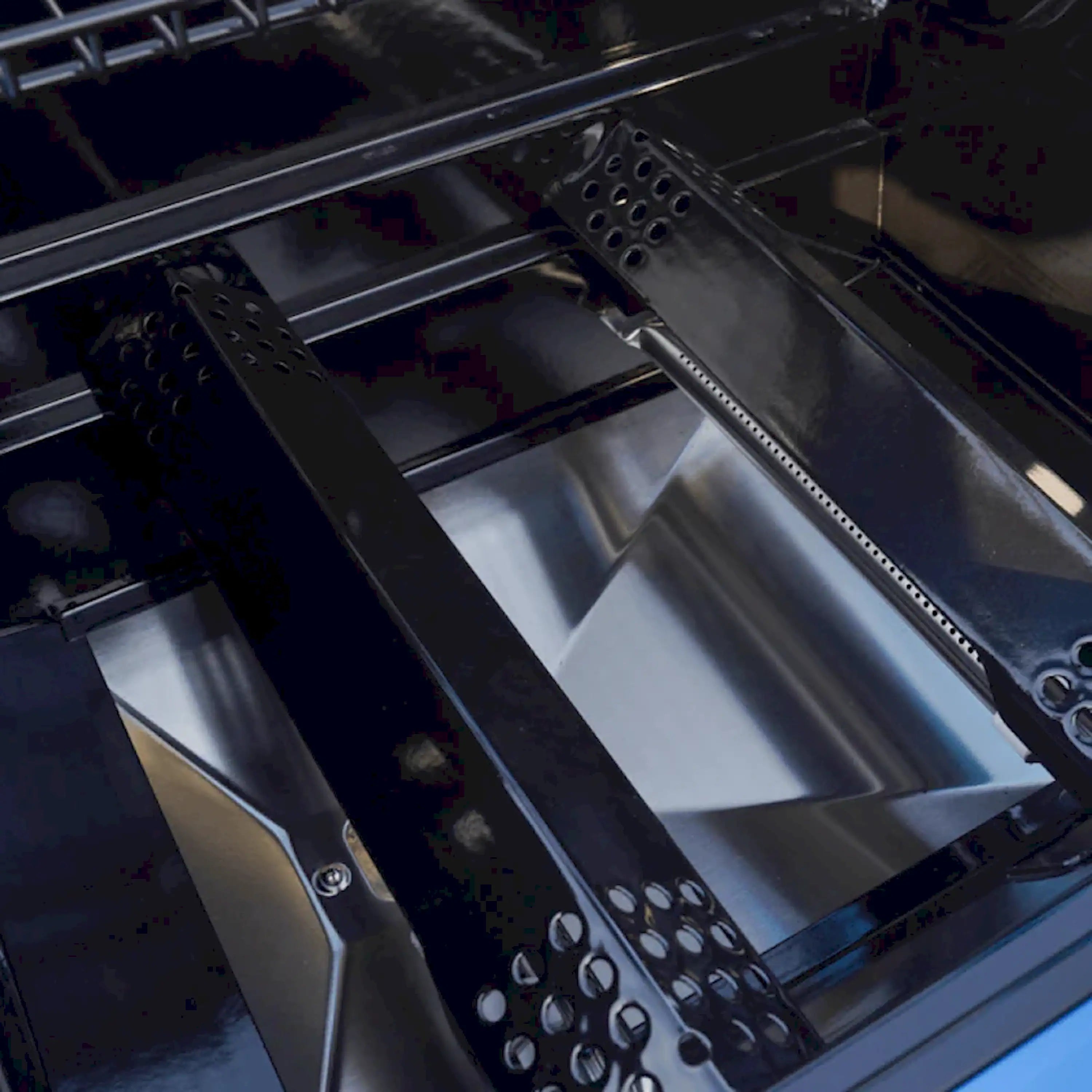 Interior view of propane grill with stainless heat shield and burner area