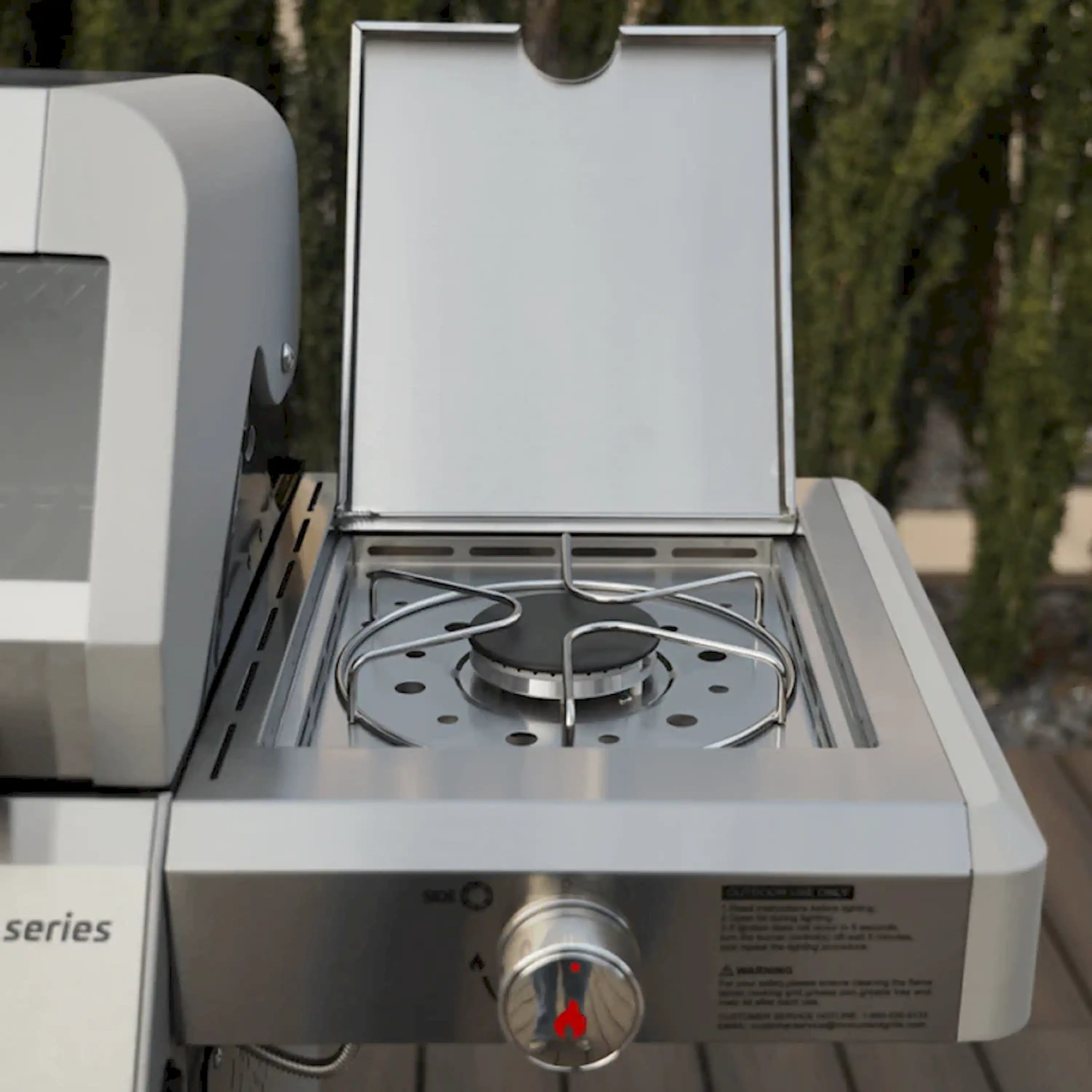 Stainless steel propane grill with open hood and front burner grate
