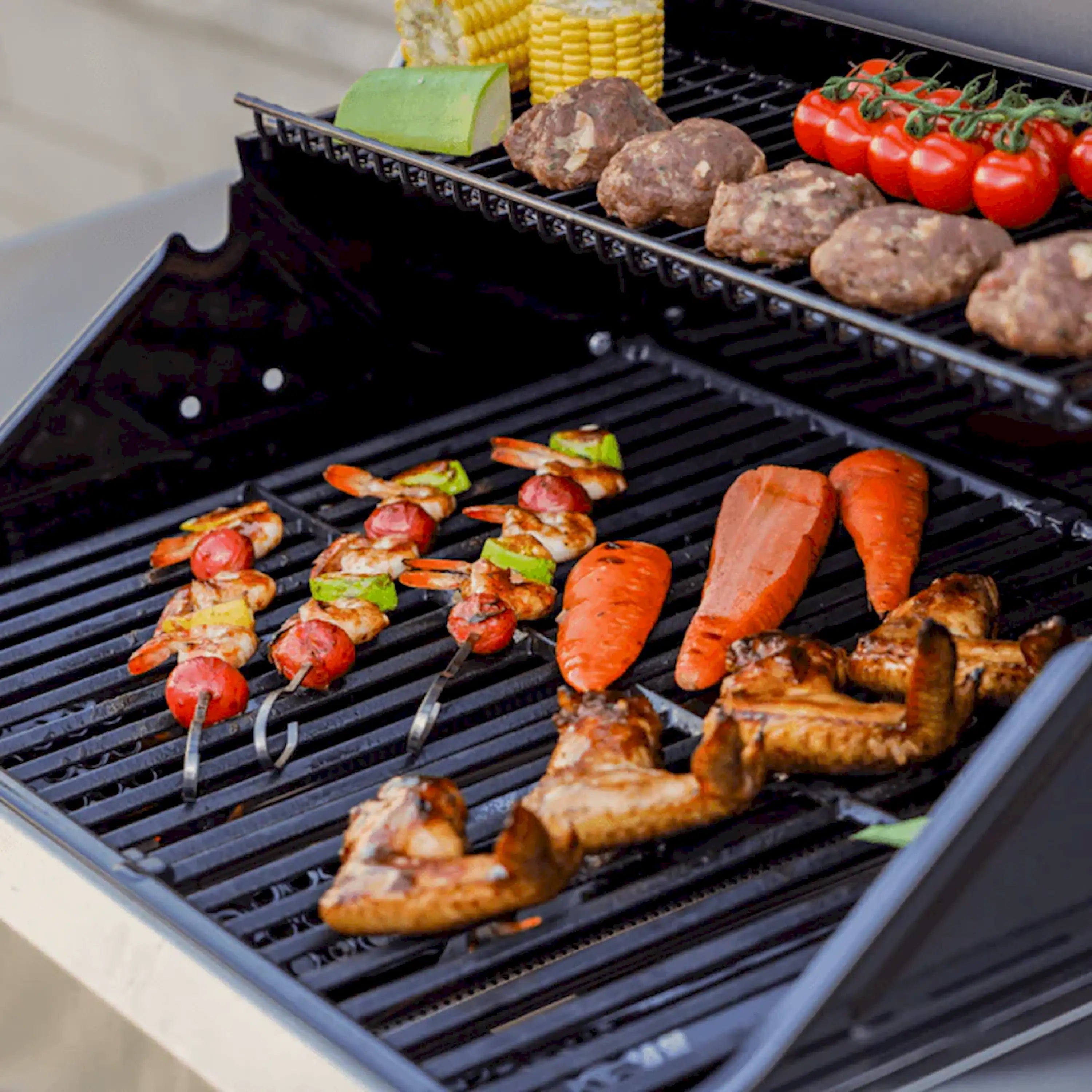 Propane grill cooking grates with sizzling sausages and vegetable skewers