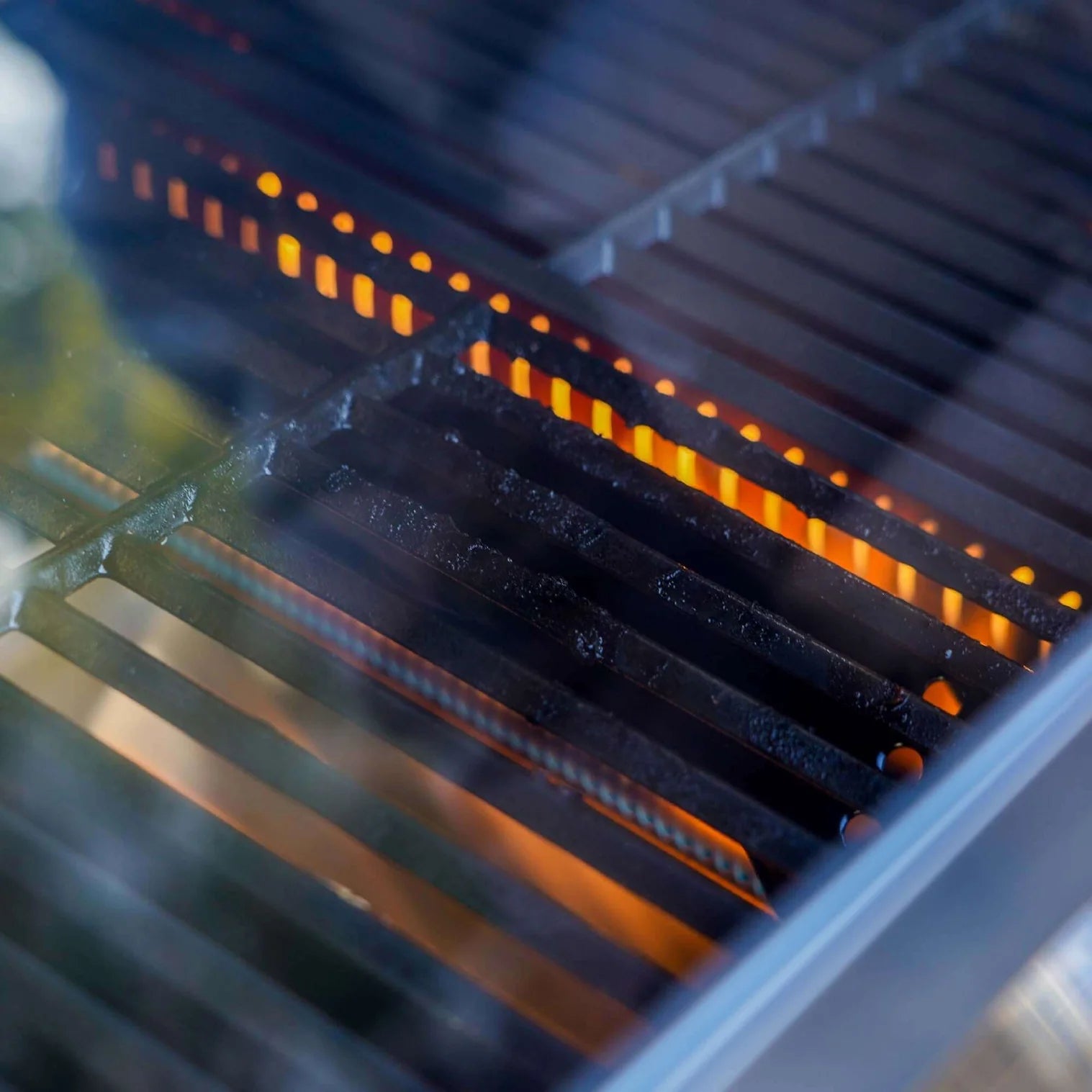 Glowing orange flames rising under the dark grill grates during cooking