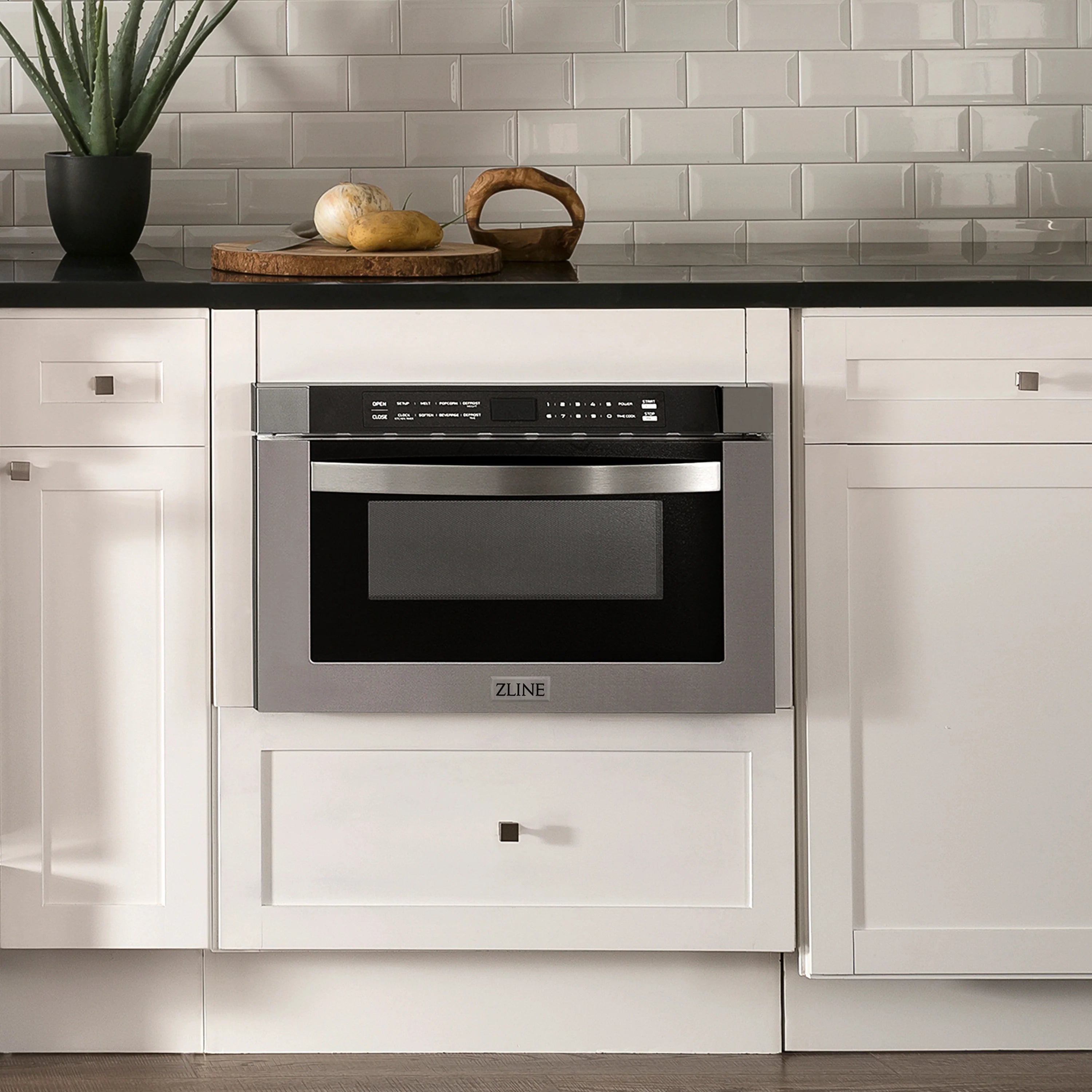 Stainless steel built-in microwave drawer with black glass door, integrated in kitchen