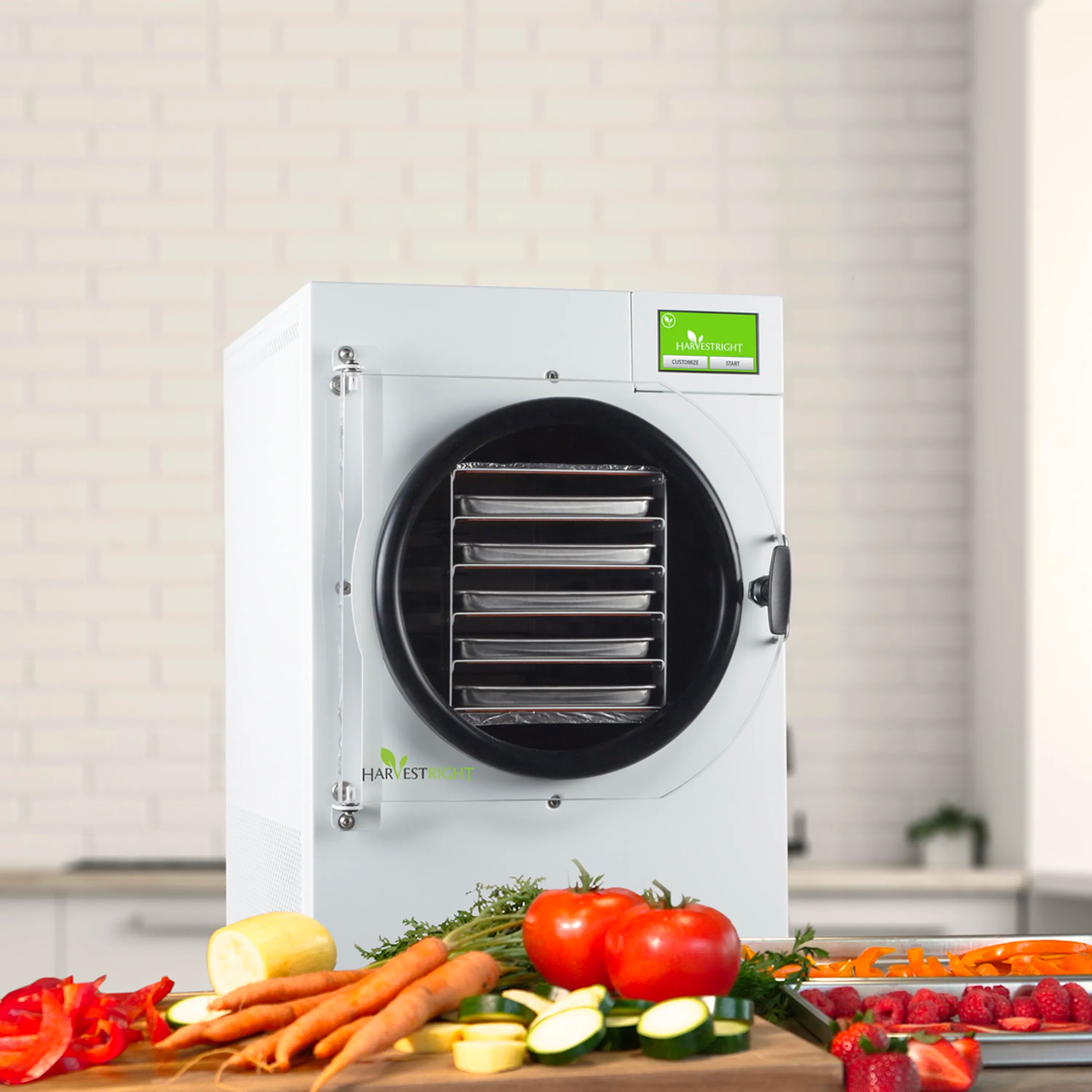 White freeze dryer with round black chamber and food trays of fresh produce