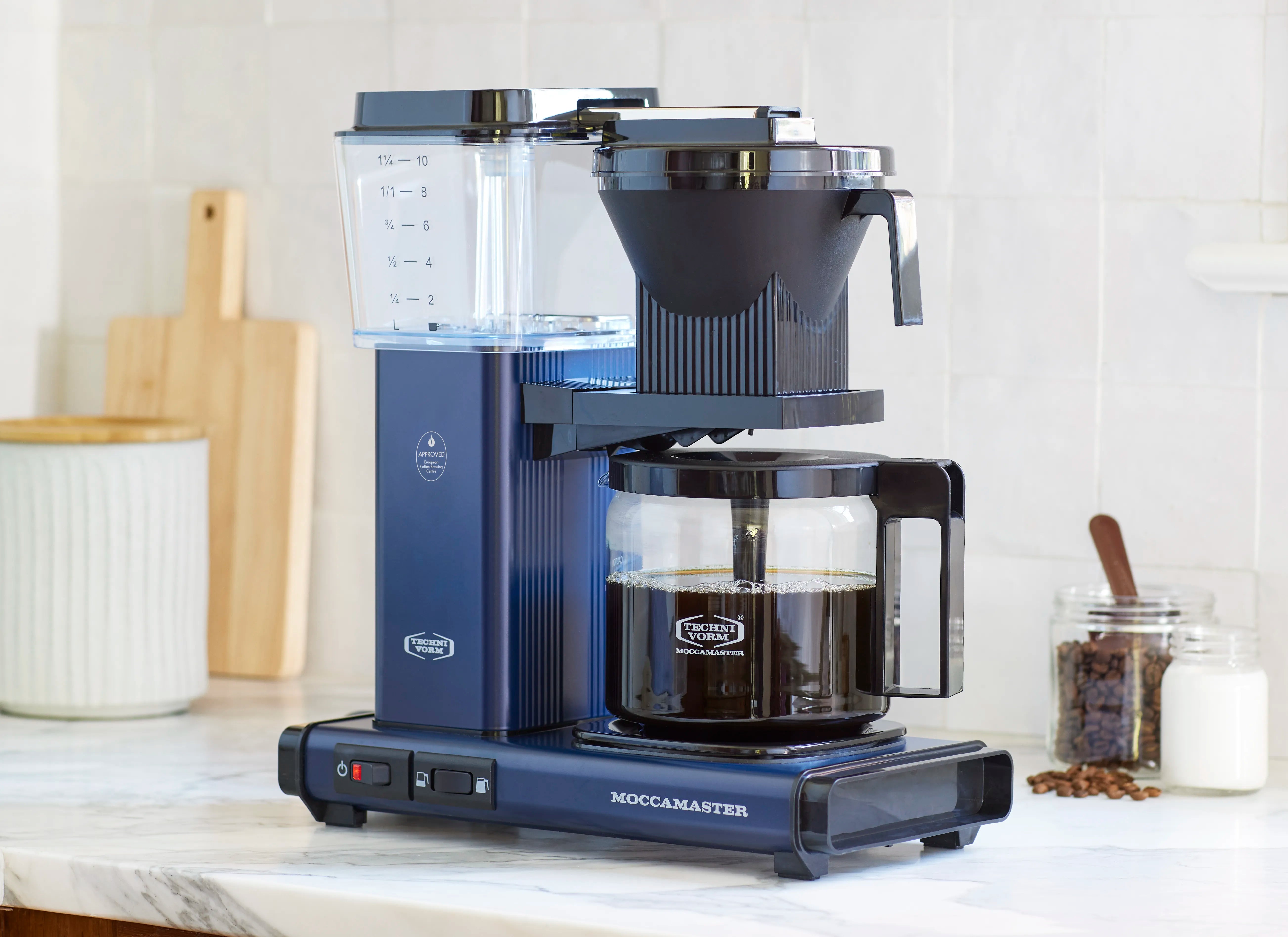 Midnight blue coffee maker with clear water tank and glass carafe on countertop