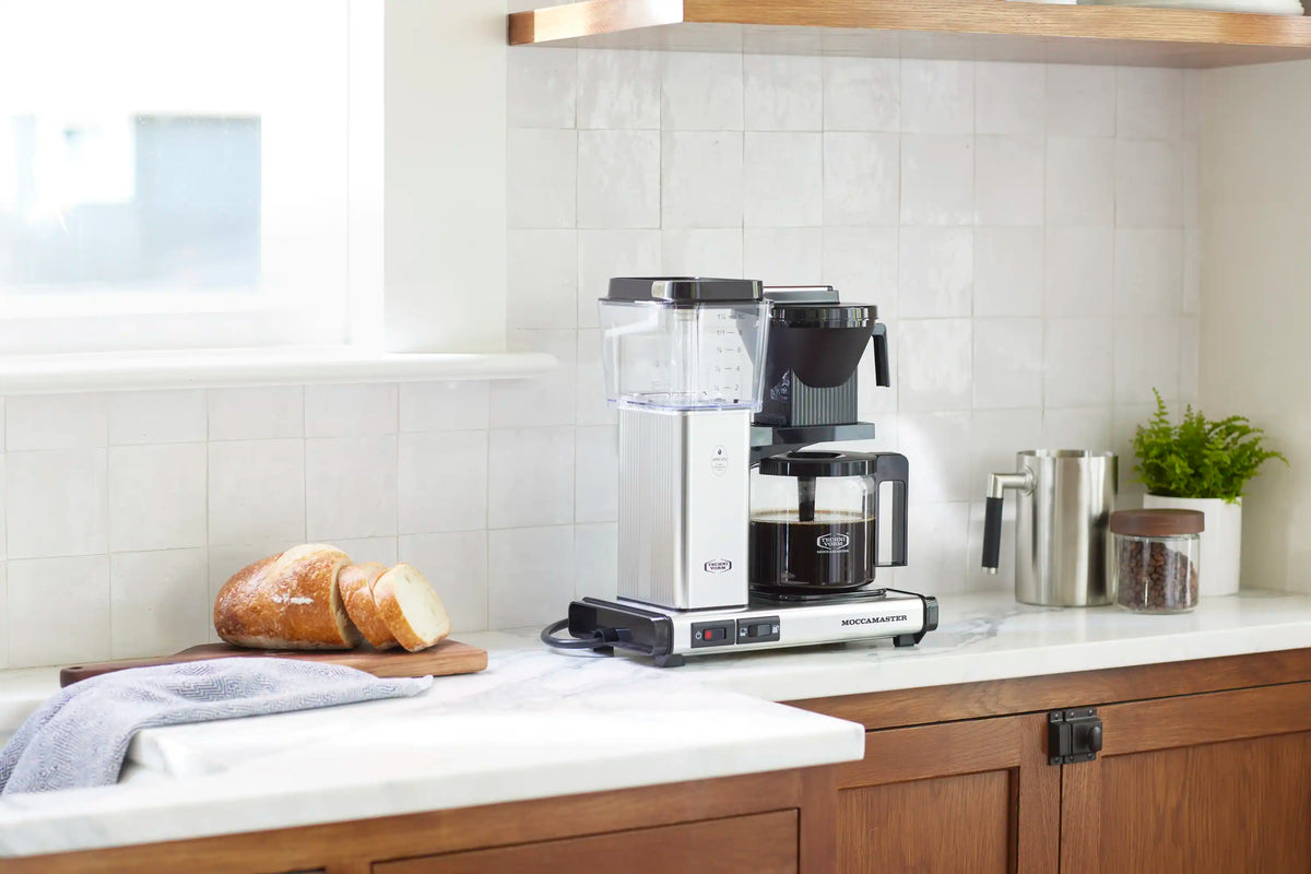 Moccamaster 10-cup coffee maker with glass carafe, black brew basket, polished silver finish.
