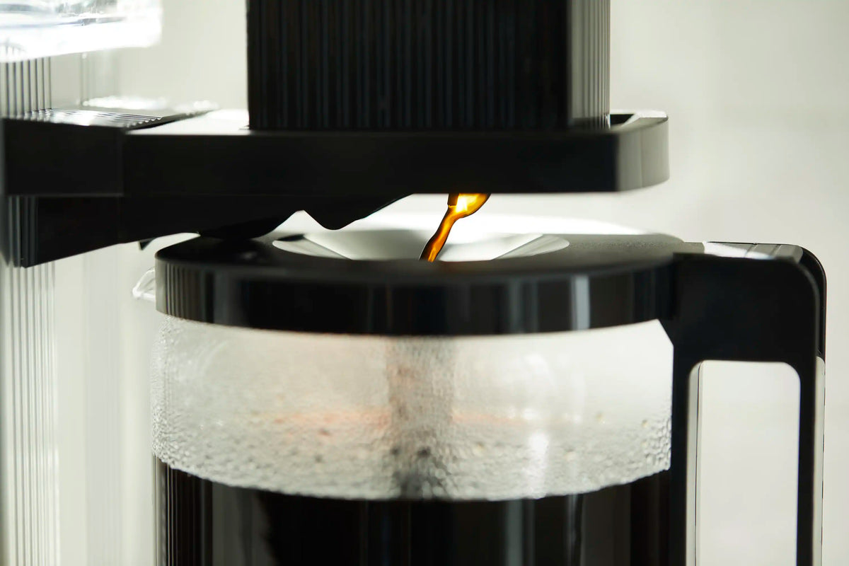 Moccamaster brewer pouring into glass carafe with black frame and carafe markings