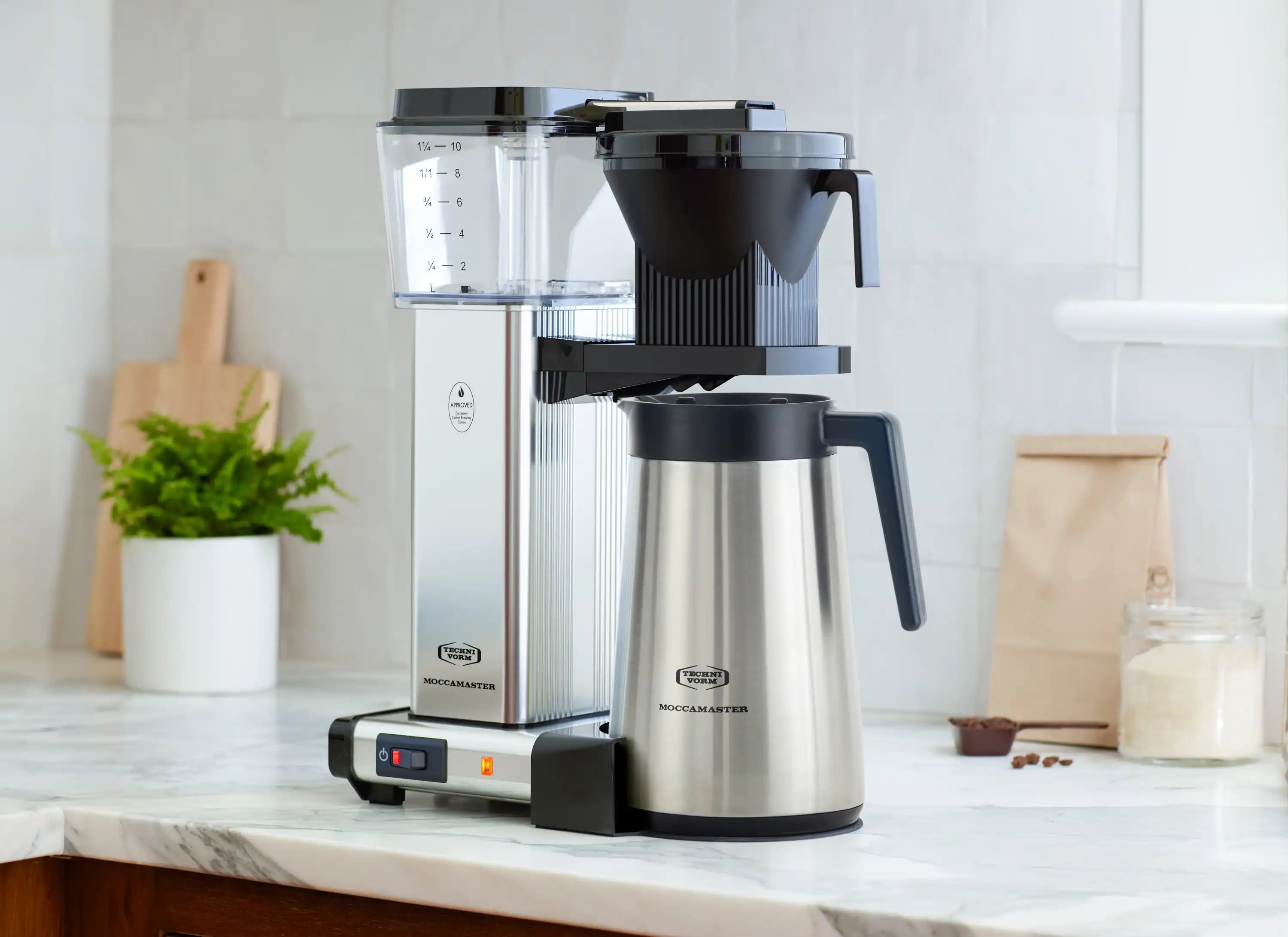 Moccamaster coffee maker with silver base, clear reservoir, black brew basket, thermal carafe