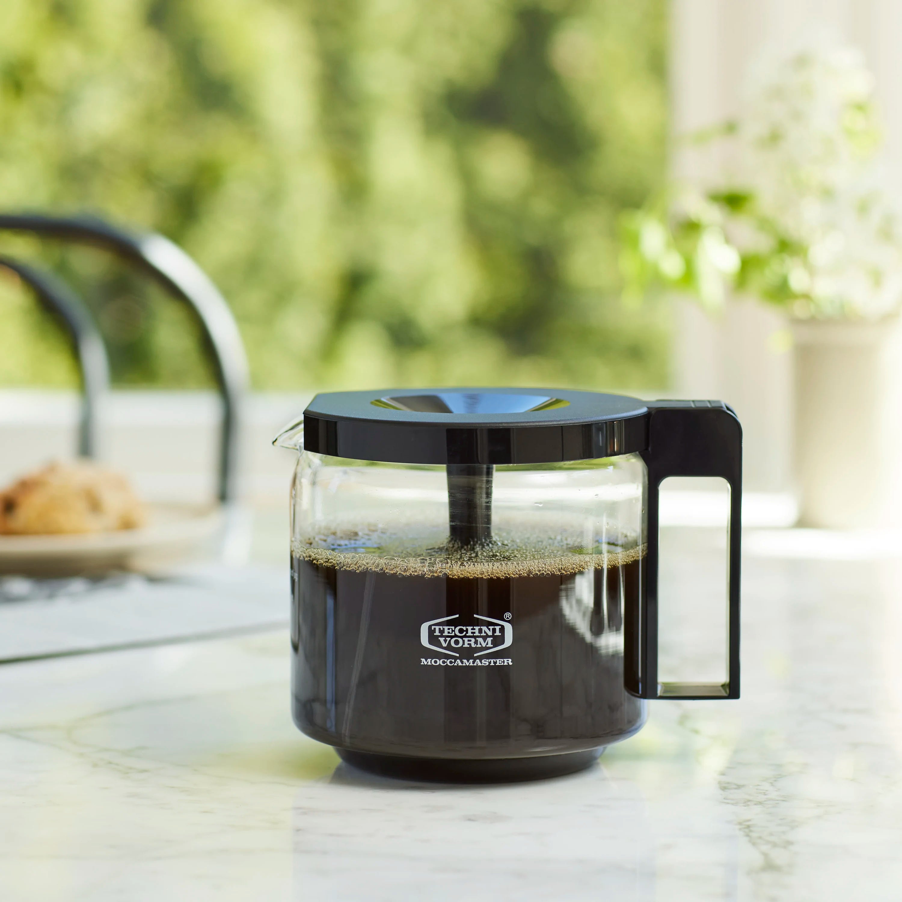 Moccamaster glass coffee carafe with black lid, black coffee level inside, 1.25 L