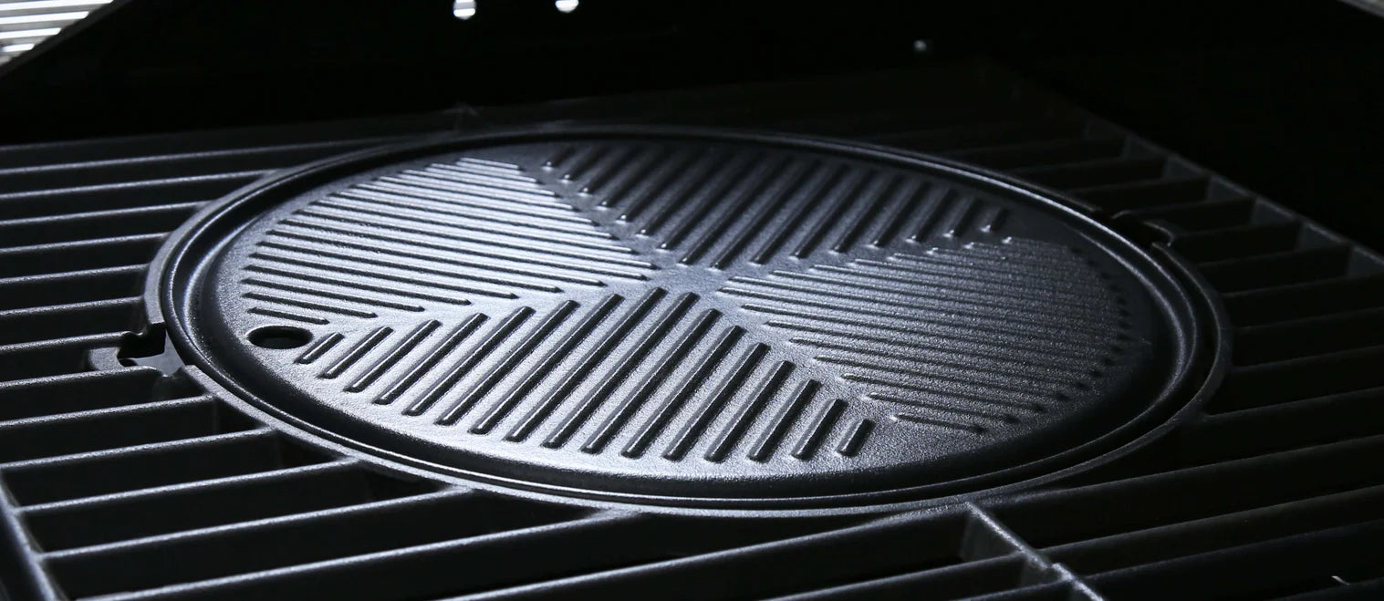 Round cast iron cooking plate close-up on grill grate with diagonal ridges