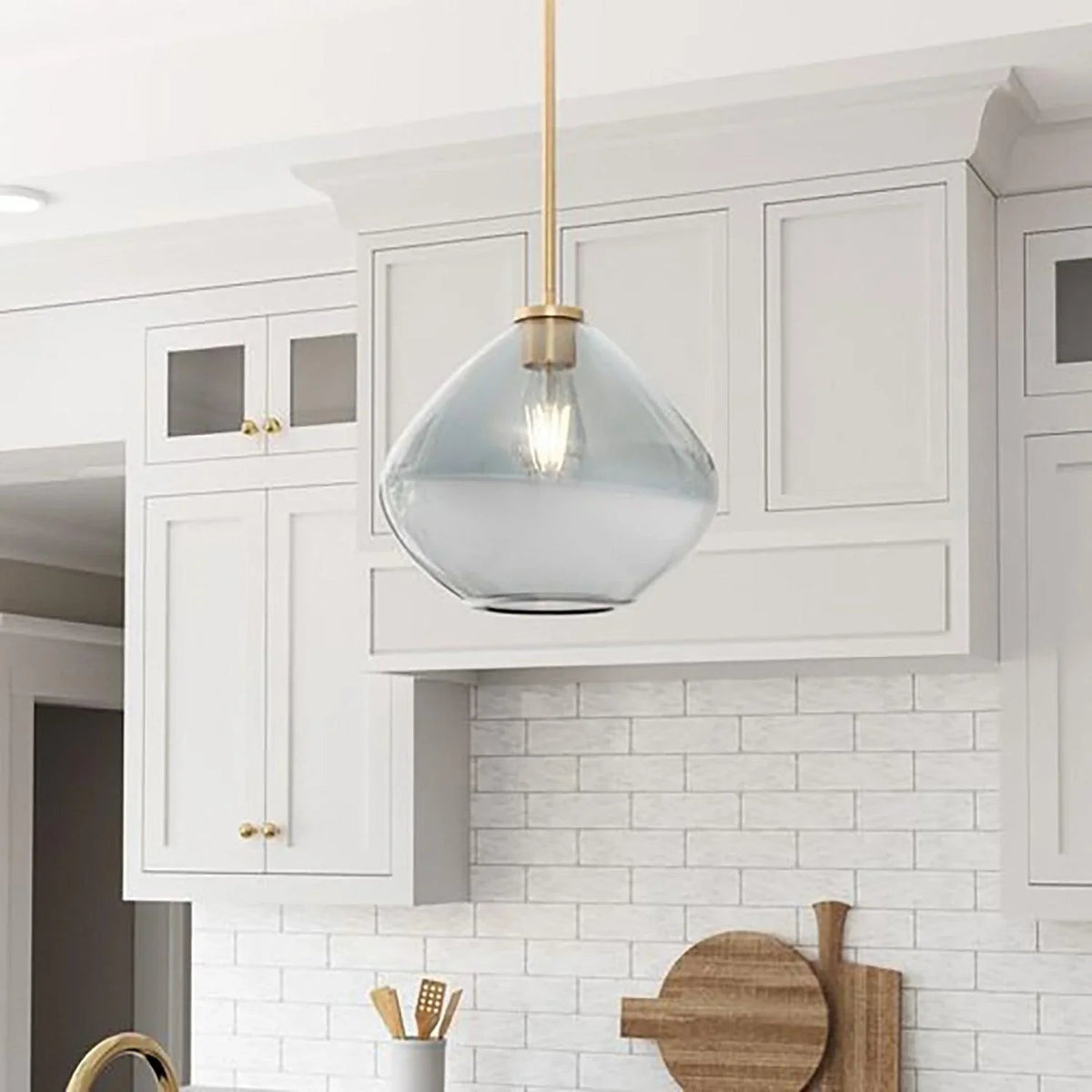Clear smoky handblown glass pendant light with golden stem in a kitchen