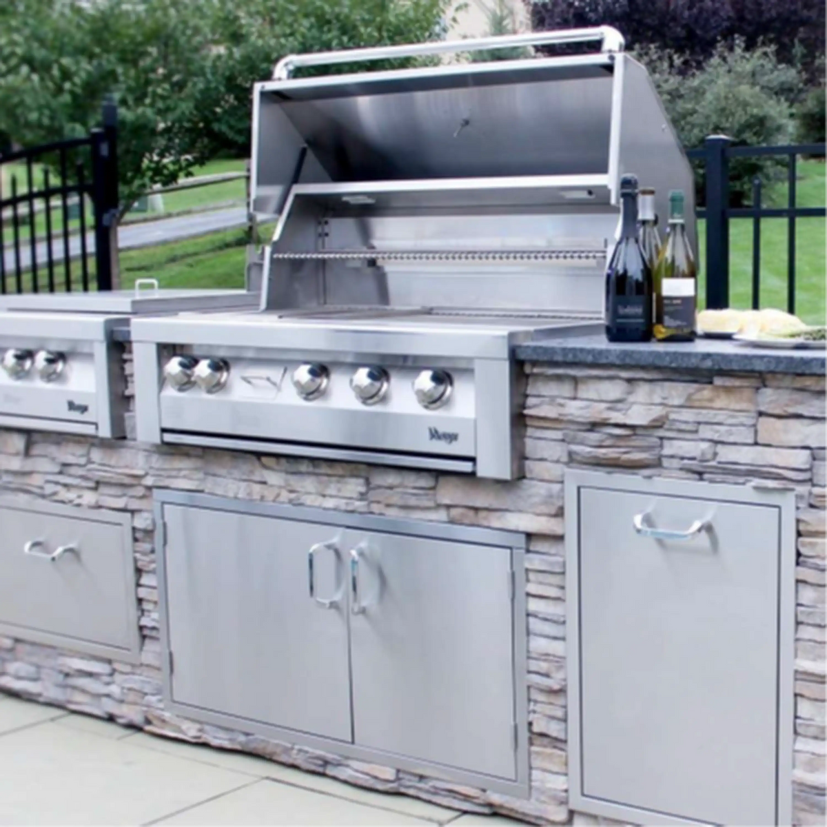 Stainless built-in natural gas grill with control knobs and two cabinet doors