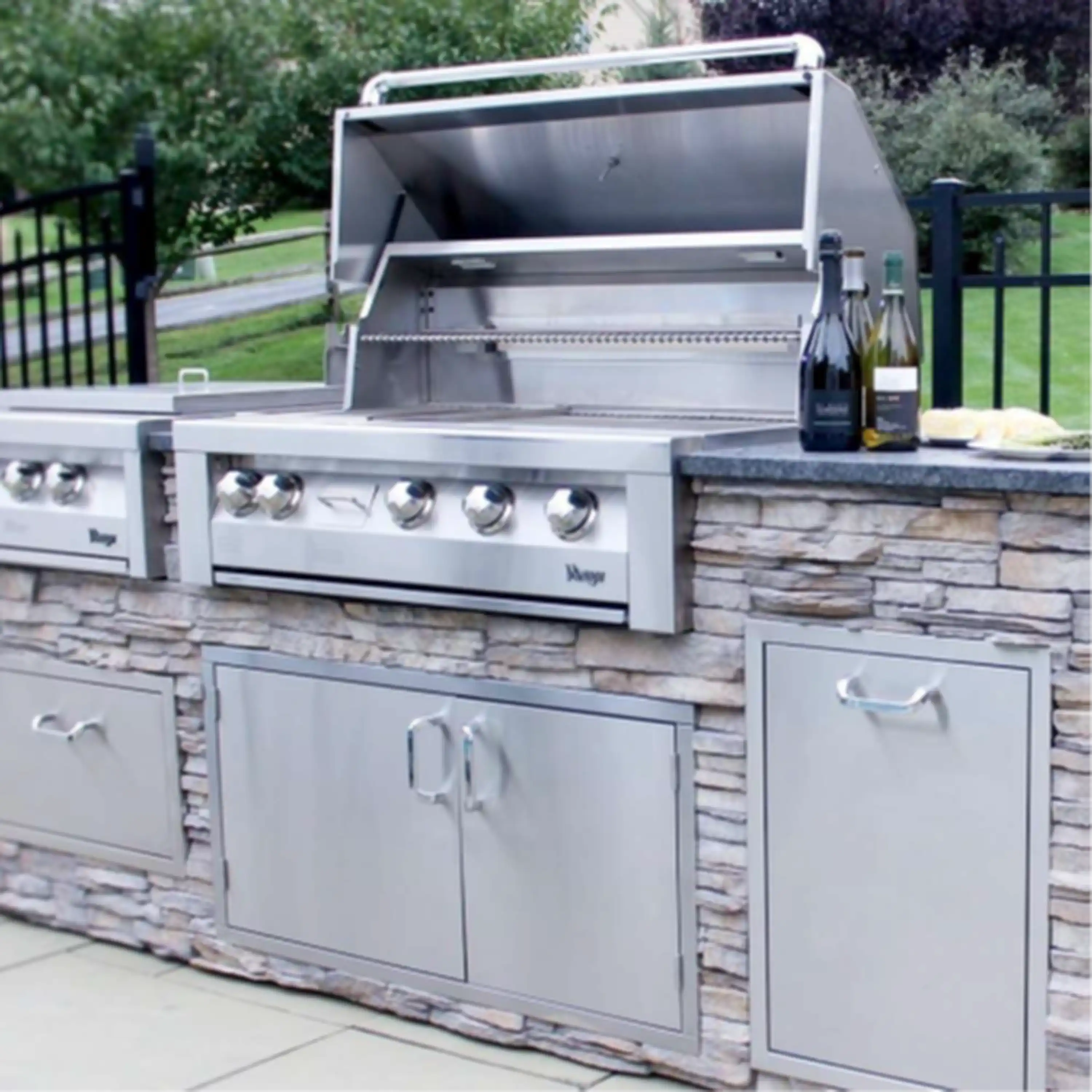 Stainless steel built-in natural gas grill with control knobs and side storage doors