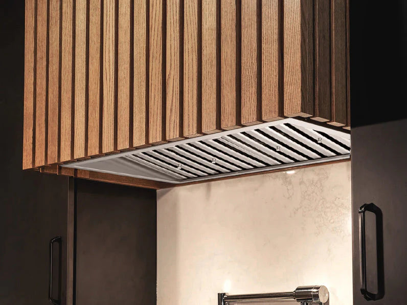 Stainless steel range hood insert installed under wood cabinets with vent grille