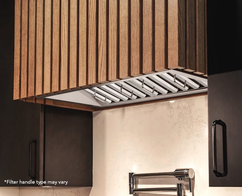 Stainless steel range hood insert under a wood cabinet with visible vent grille