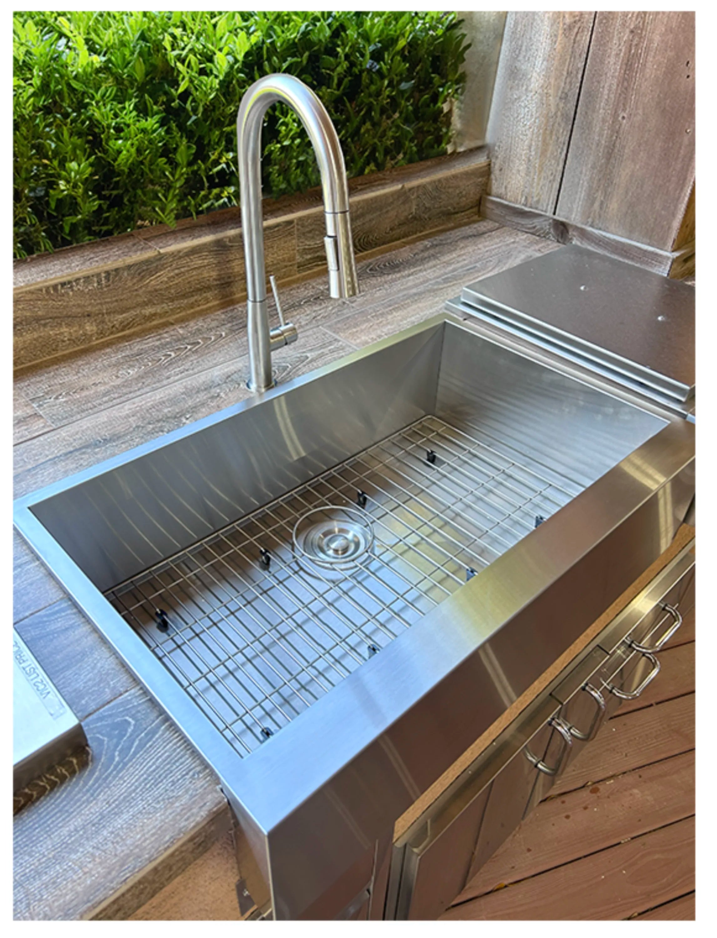 Outdoor sink with wire grate and circular drain in stainless basin