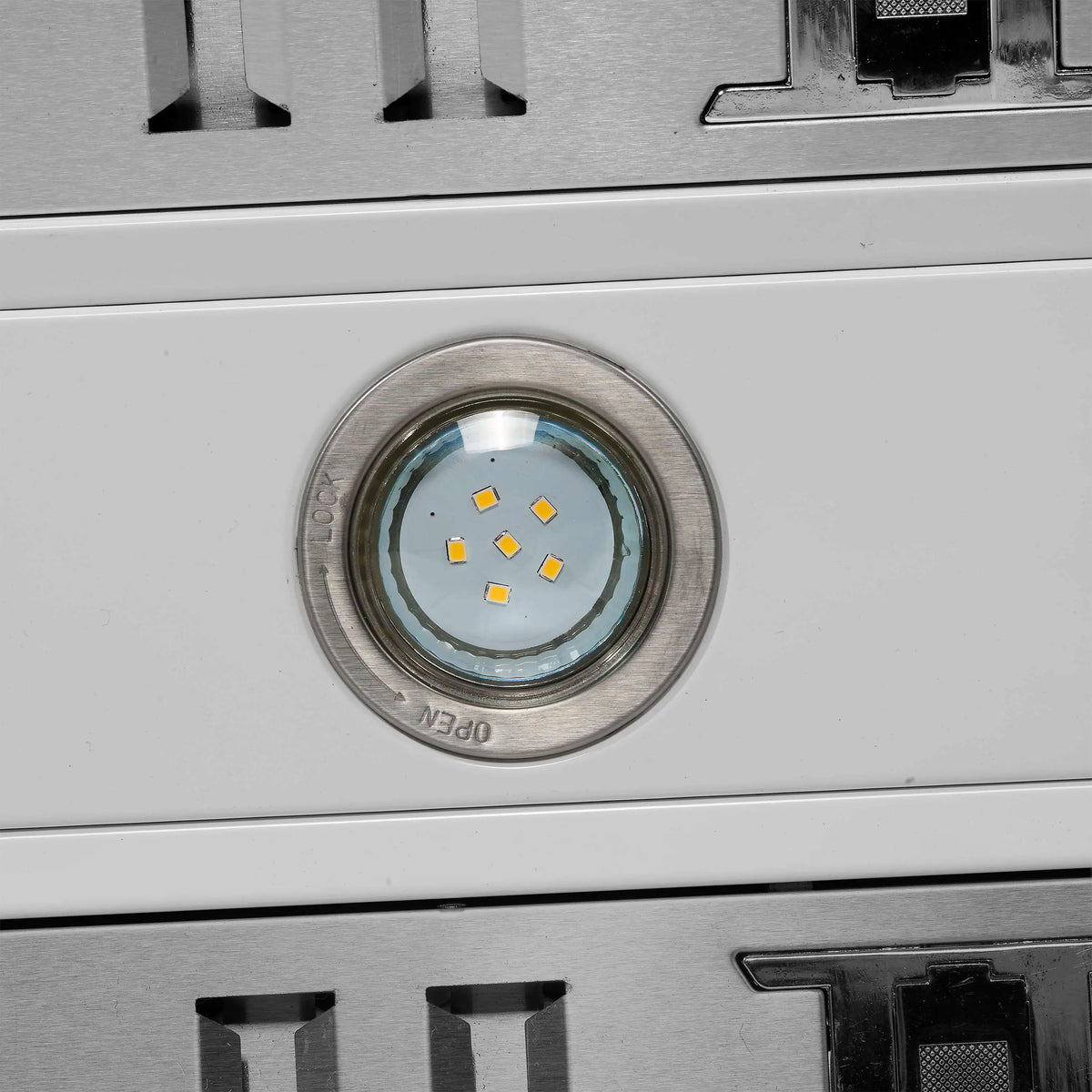 Stainless steel oven door area with circular cooktop light and vent openings