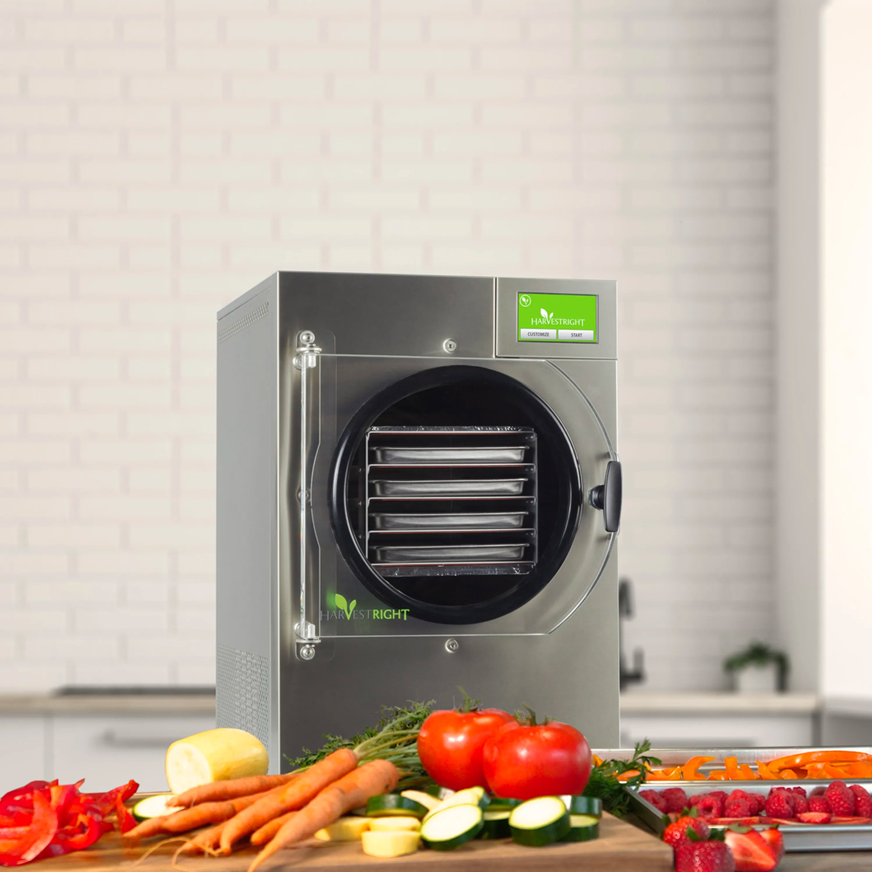 Stainless steel freeze dryer with round door and fresh produce arranged on countertop