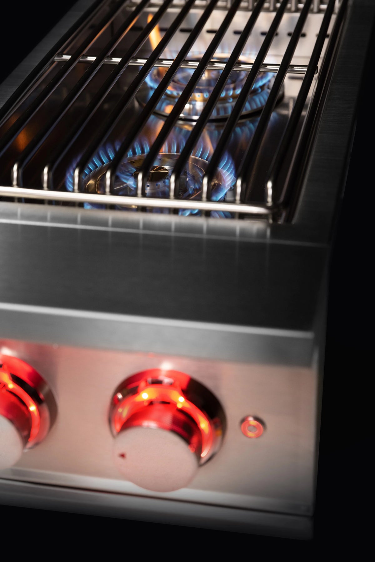 Double natural gas side burner grate showing blue flames under the burner hood