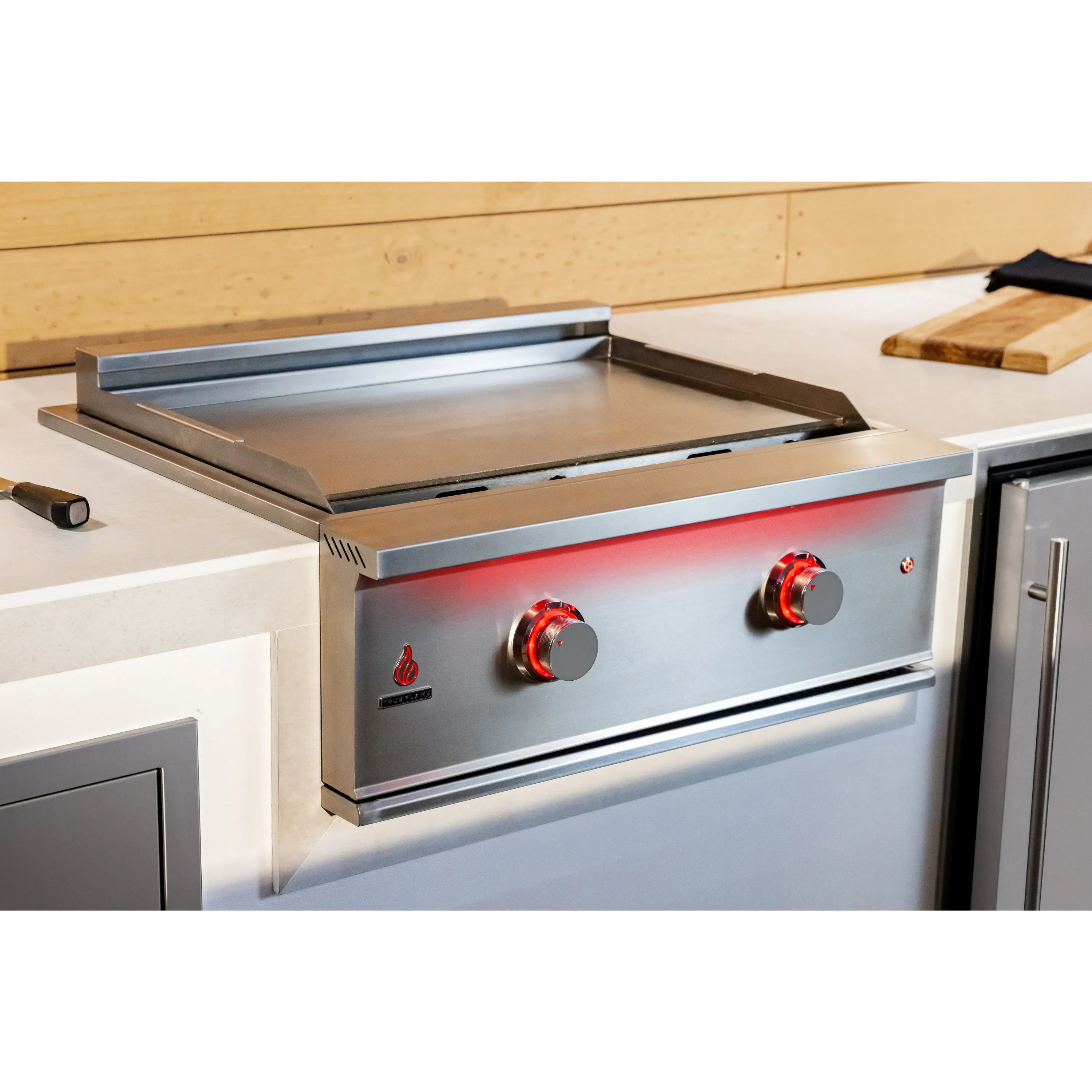 Installed stainless gas griddle with open lid, red burner strip, and two control knobs