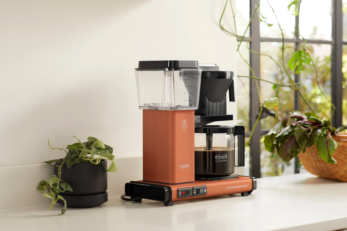 Terracotta drip coffee maker with glass carafe on base, black brew cone