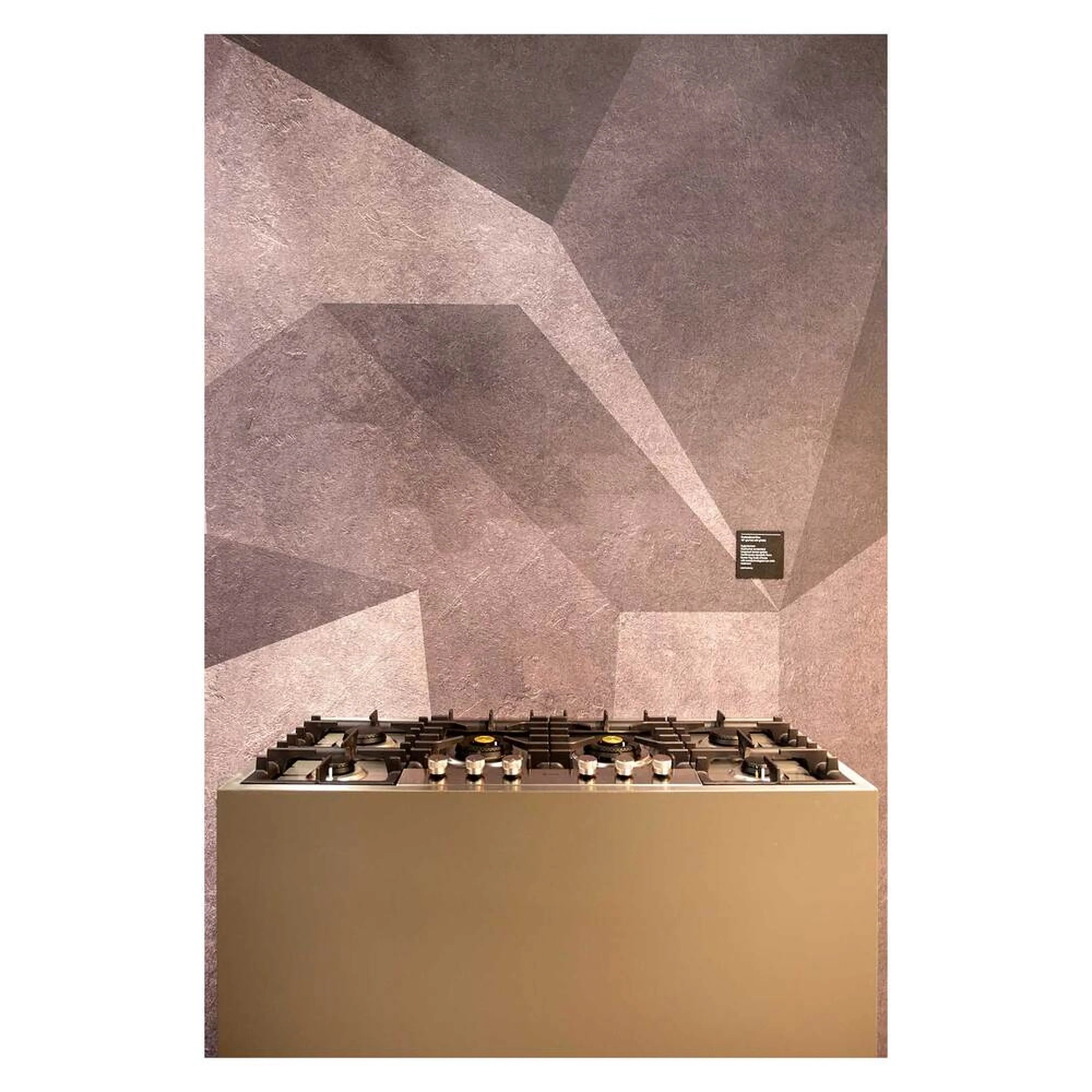 Built-in stainless steel gas cooktop with black burner grates and brass caps.