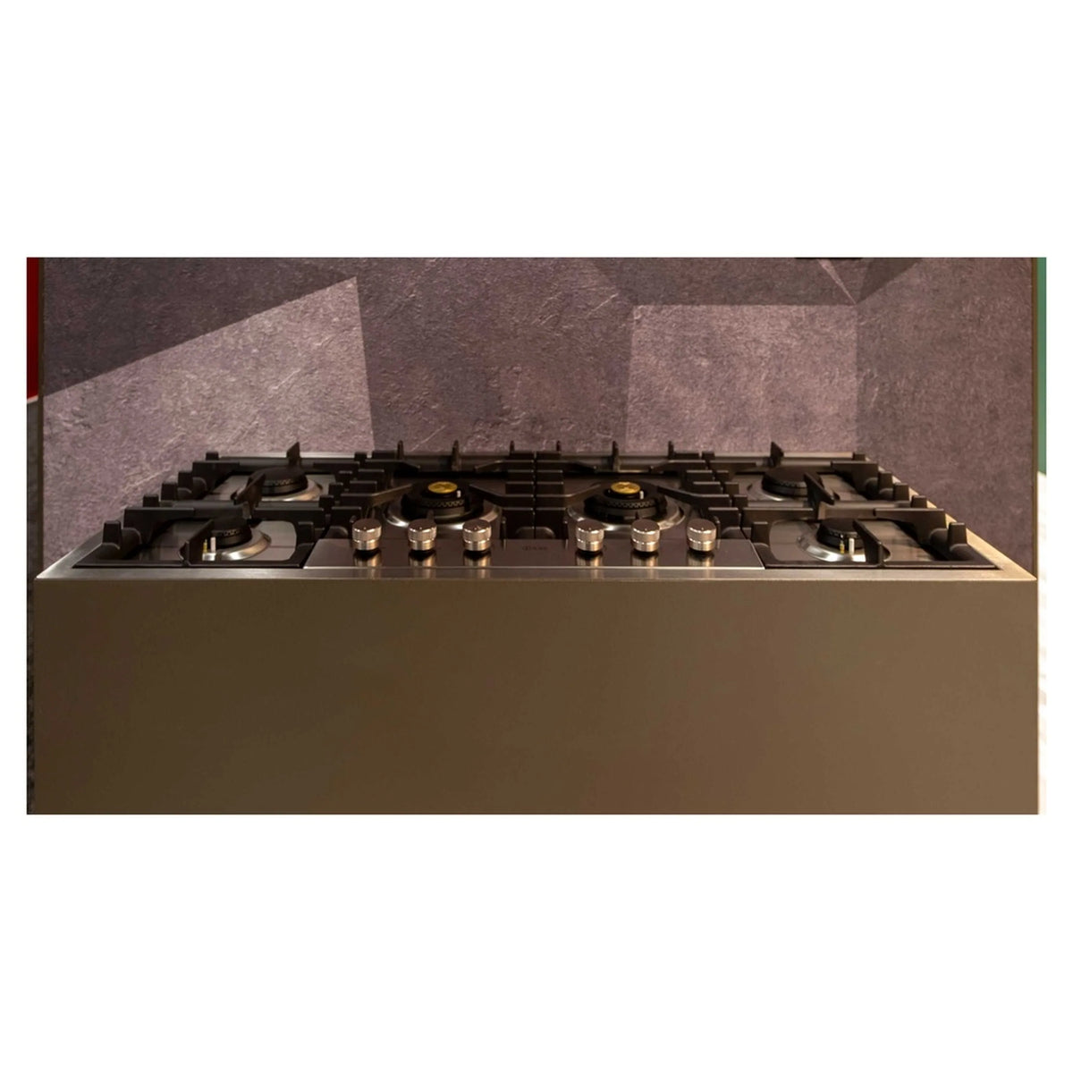 Stainless steel built-in gas cooktop with black grates and brass burner caps.