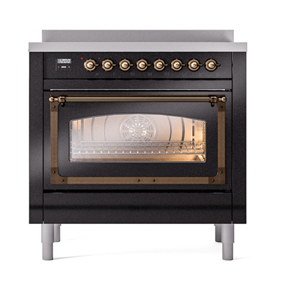 Glossy black induction range with lit oven interior visible through glass door; bronze knobs.