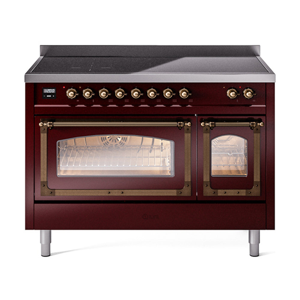 Burgundy induction range front with bronze knobs and lit oven cavity behind glass