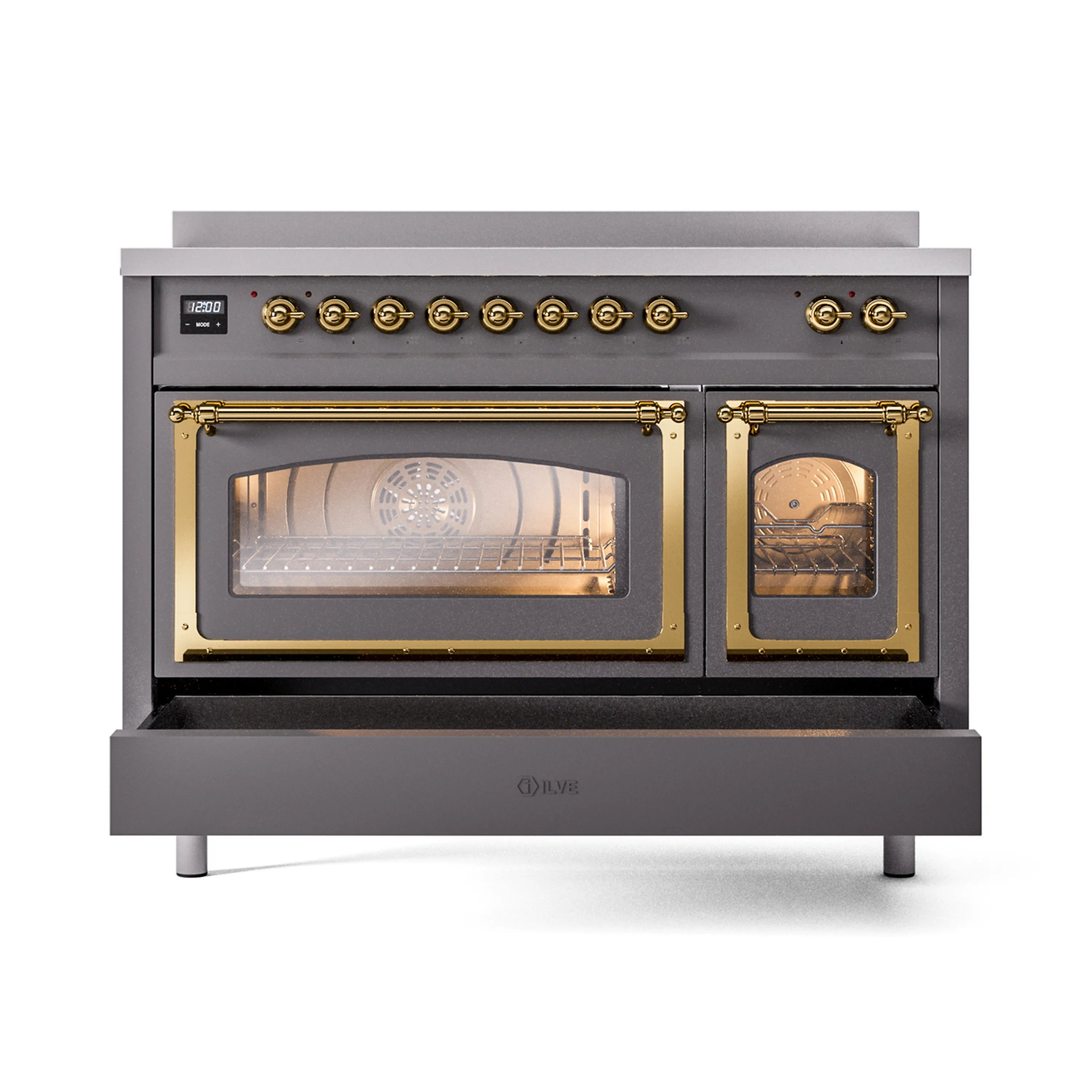 Matte graphite induction range with brass-trim oven windows showing lit interiors