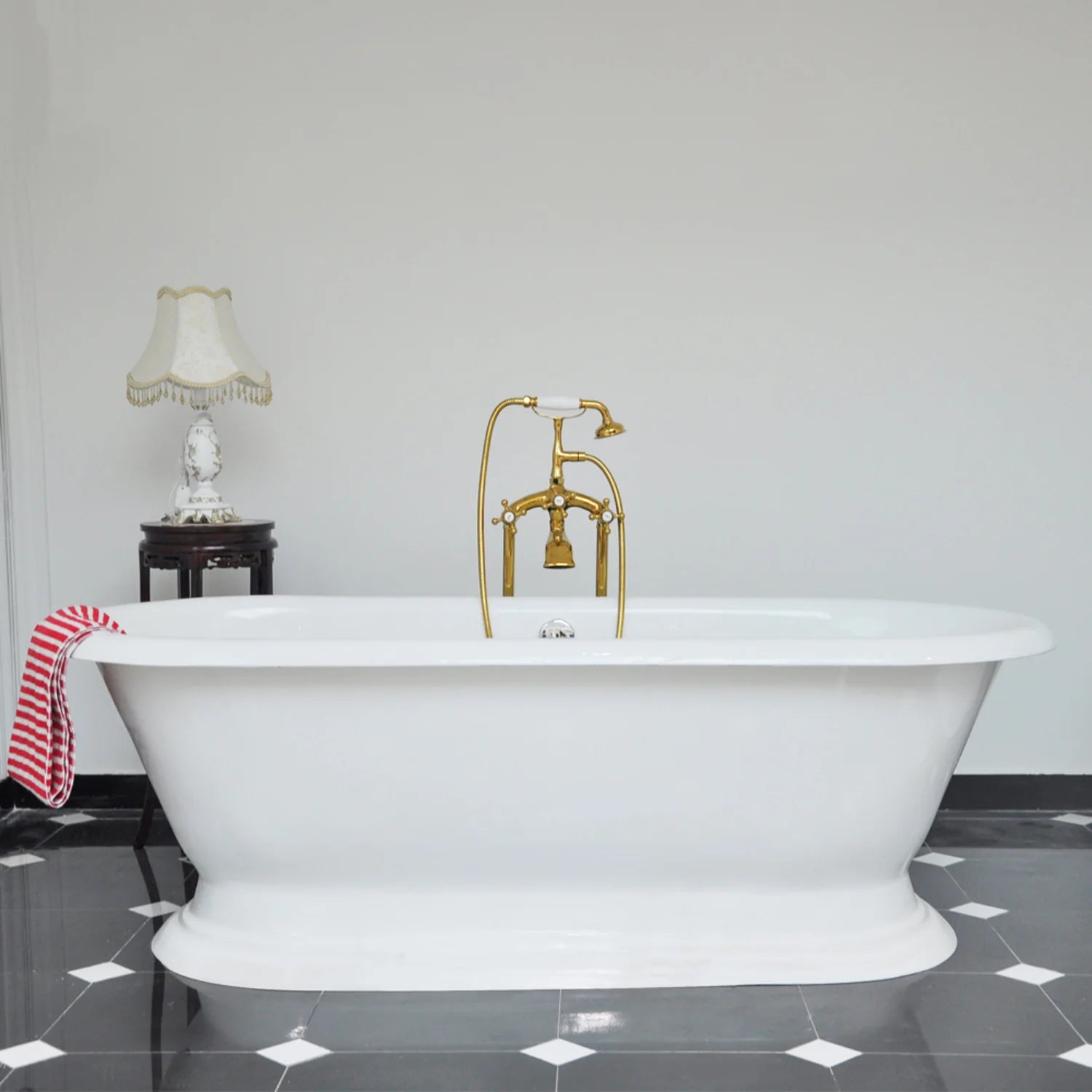 White oval freestanding pedestal bathtub with double-ended shape and rolled apron