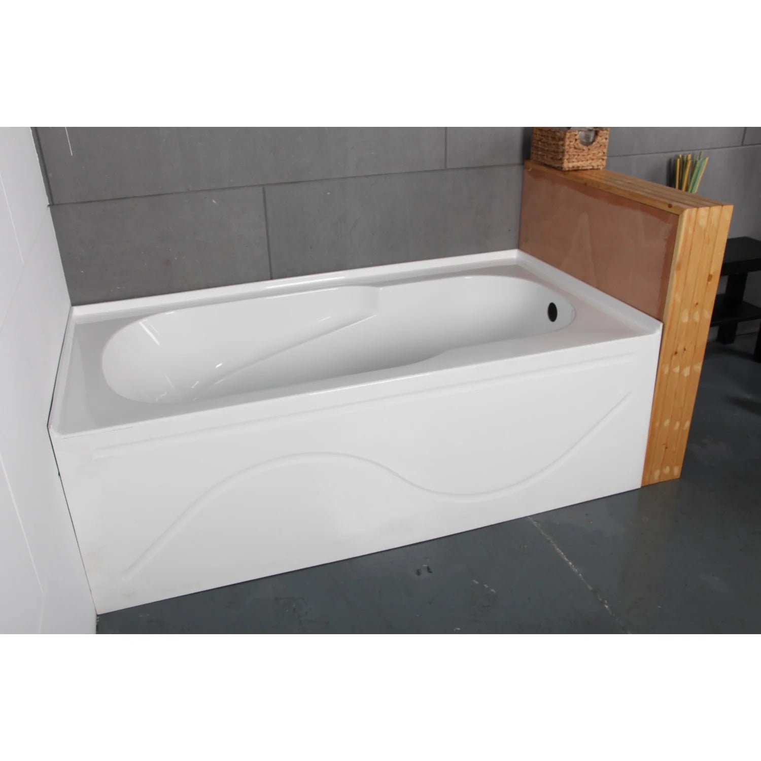 Installed glossy white acrylic alcove bathtub with right-side drain and curved apron molding