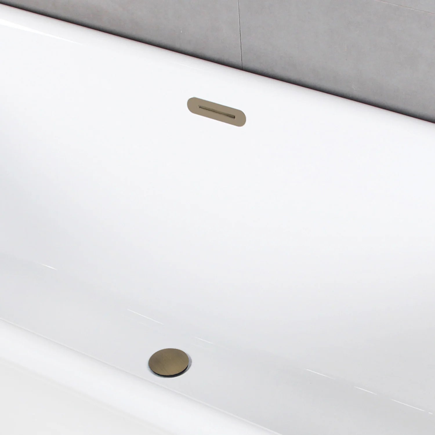 Antique brass drain opening and overflow cover on glossy white acrylic tub