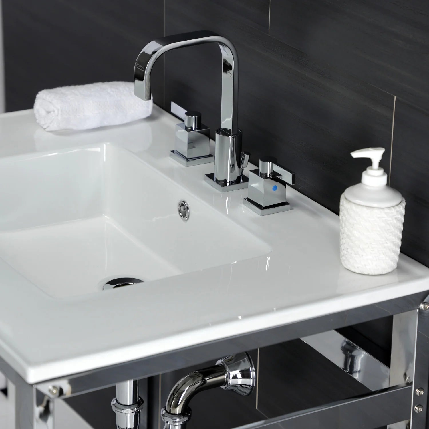 White ceramic sink basin with chrome faucet and soap dispenser on a console base