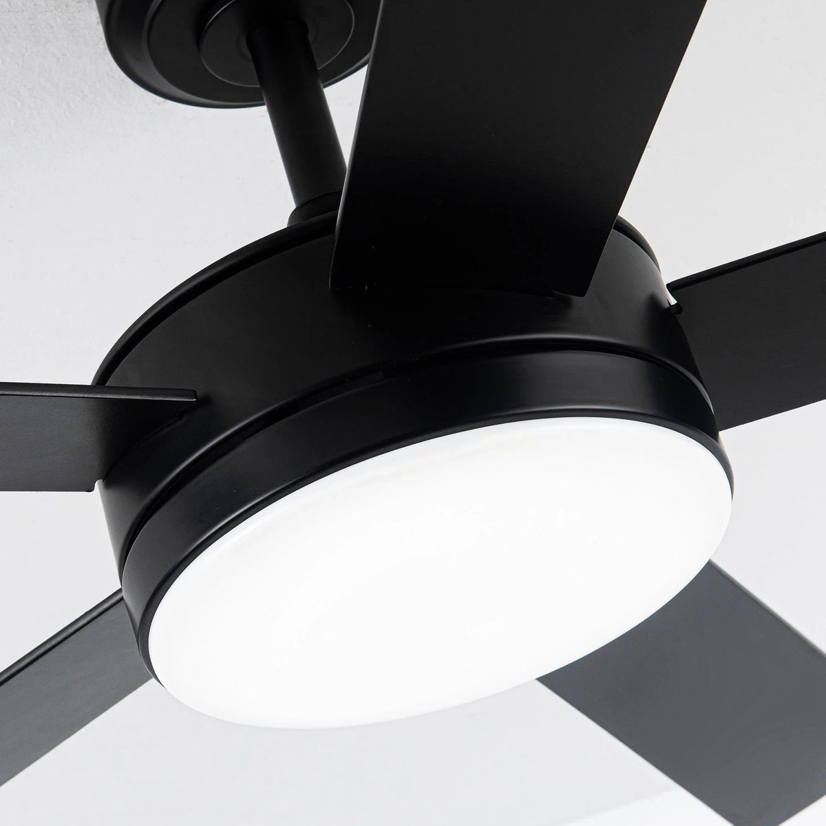 Close-up of black ceiling fan motor housing, blades, and LED light globe