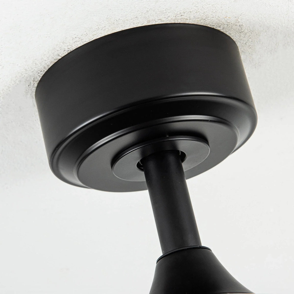 Black ceiling fan motor housing with central downrod and blade hub.