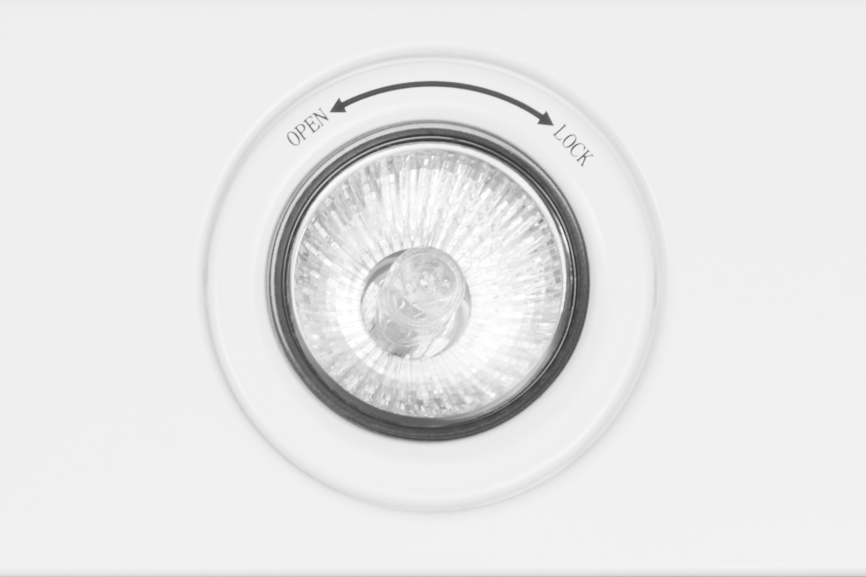 Matte white range hood fan opening with circular ring and open/lock markings.