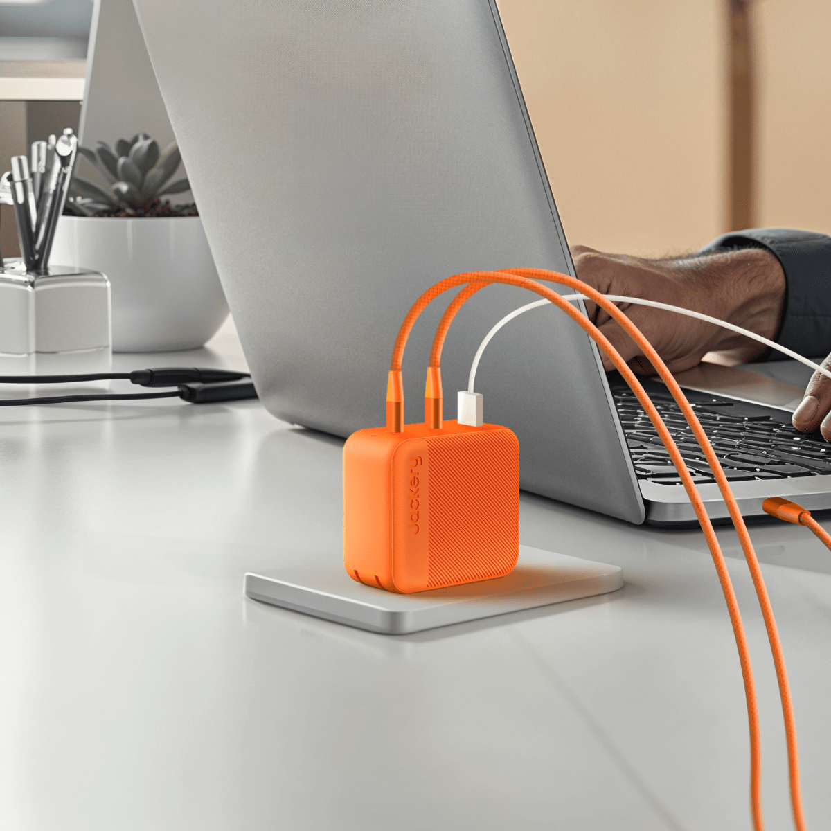 Orange fast charger cube on desk with orange USB cables plugged in