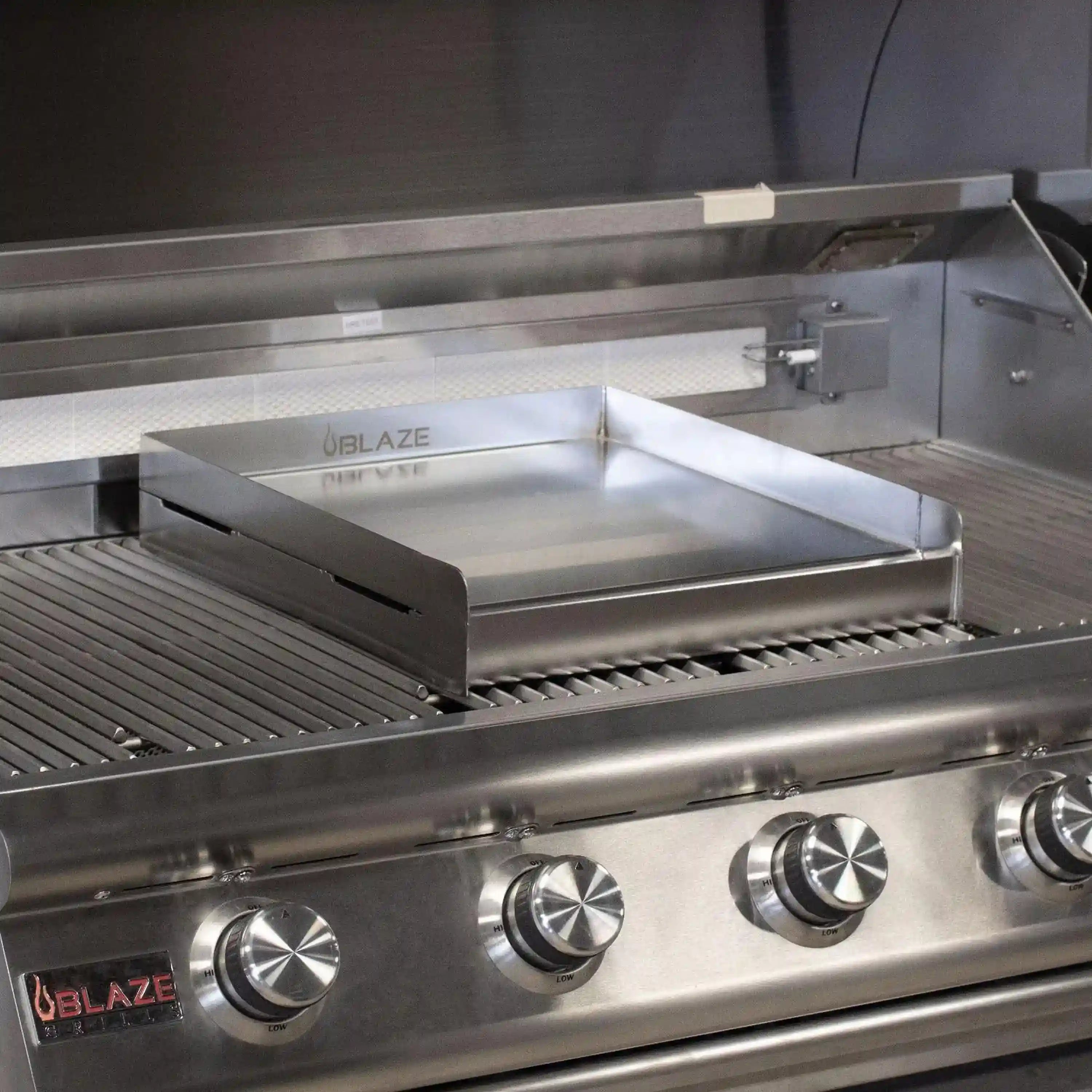Stainless steel griddle plate installed on grill grates, ready for cooking