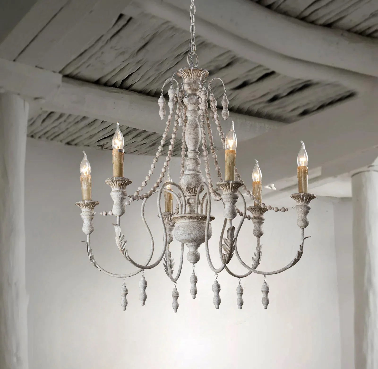Six-light chandelier with white finish, hanging beads, and ornate metal candle arms