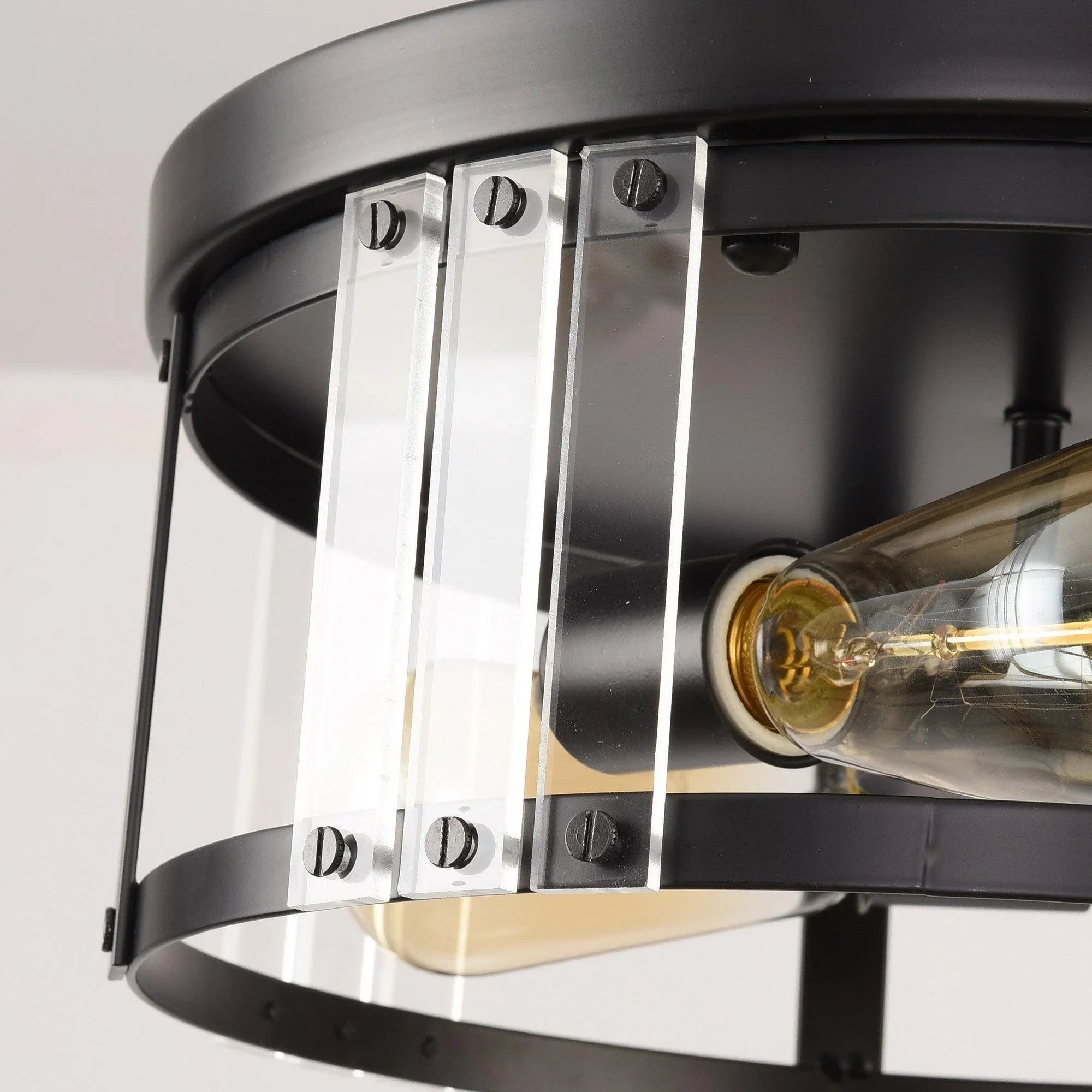 Close-up of black ceiling light hardware with clear glass panels and exposed filament bulbs