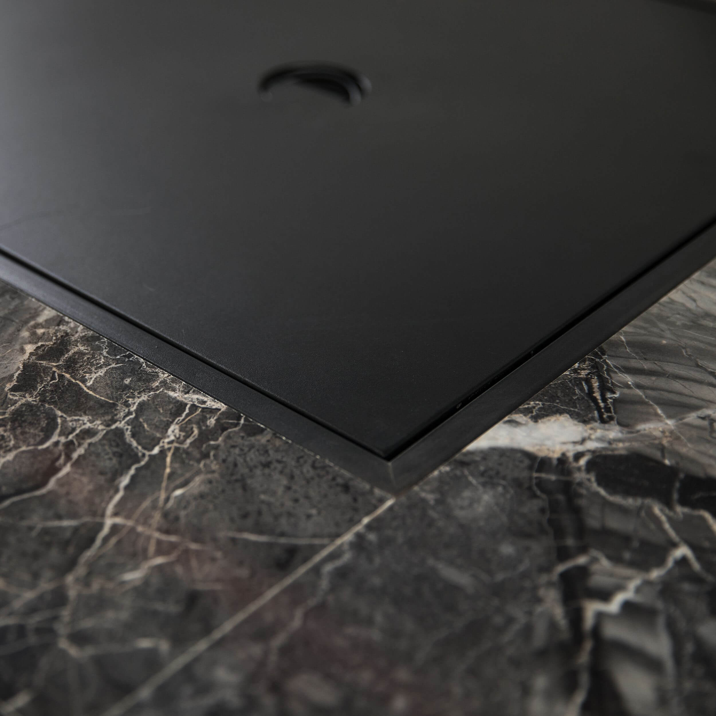 Corner detail of the firepit table: black frame border on gray stone top