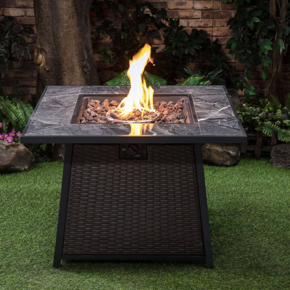 Outdoor gas firepit table with burning flames in the center of the gray stone top