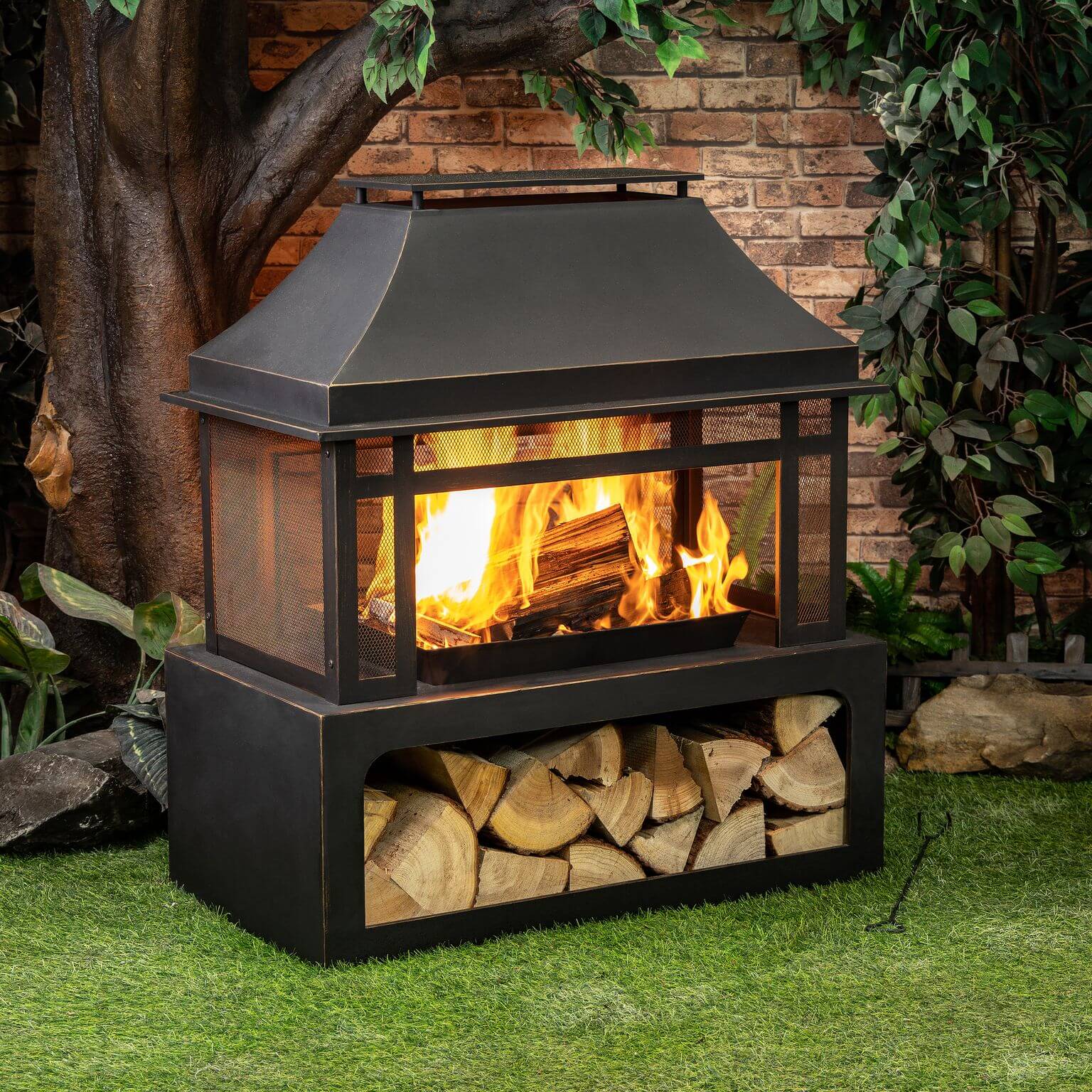 Black metal wood burner fireplace with flames in the firebox and logs in the lower tray