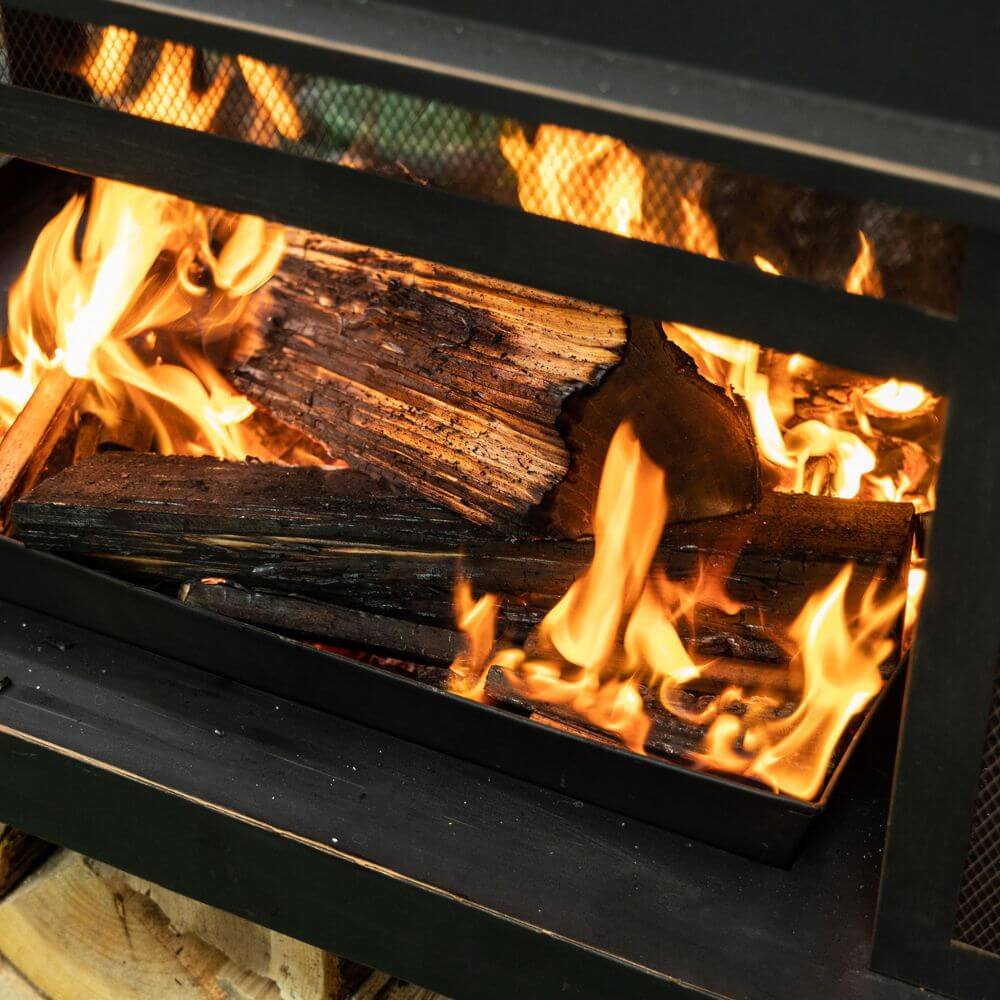 Black metal wood burner fireplace with open firebox and burning logs