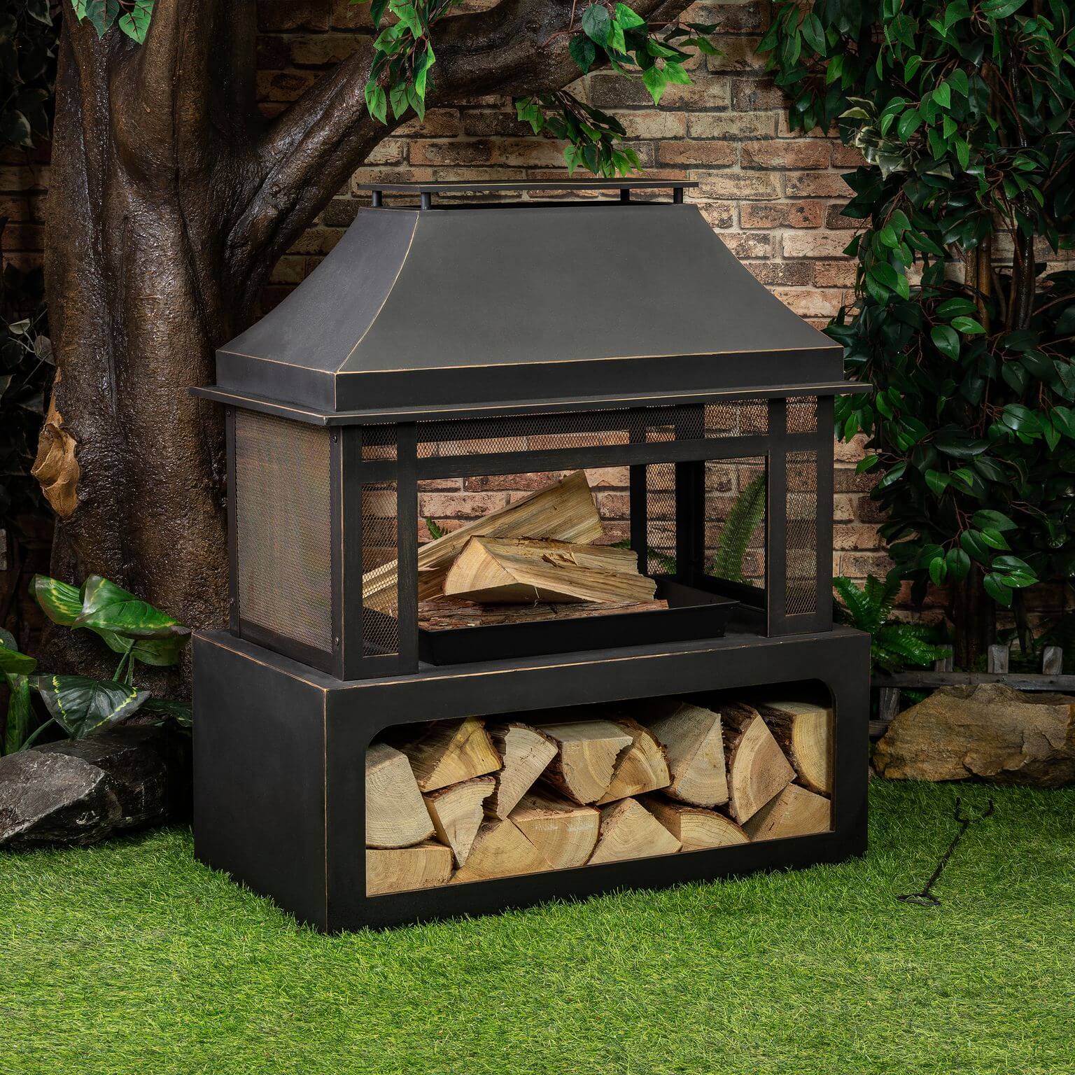 Black metal wood burner fireplace with sloped hood and stacked log compartment