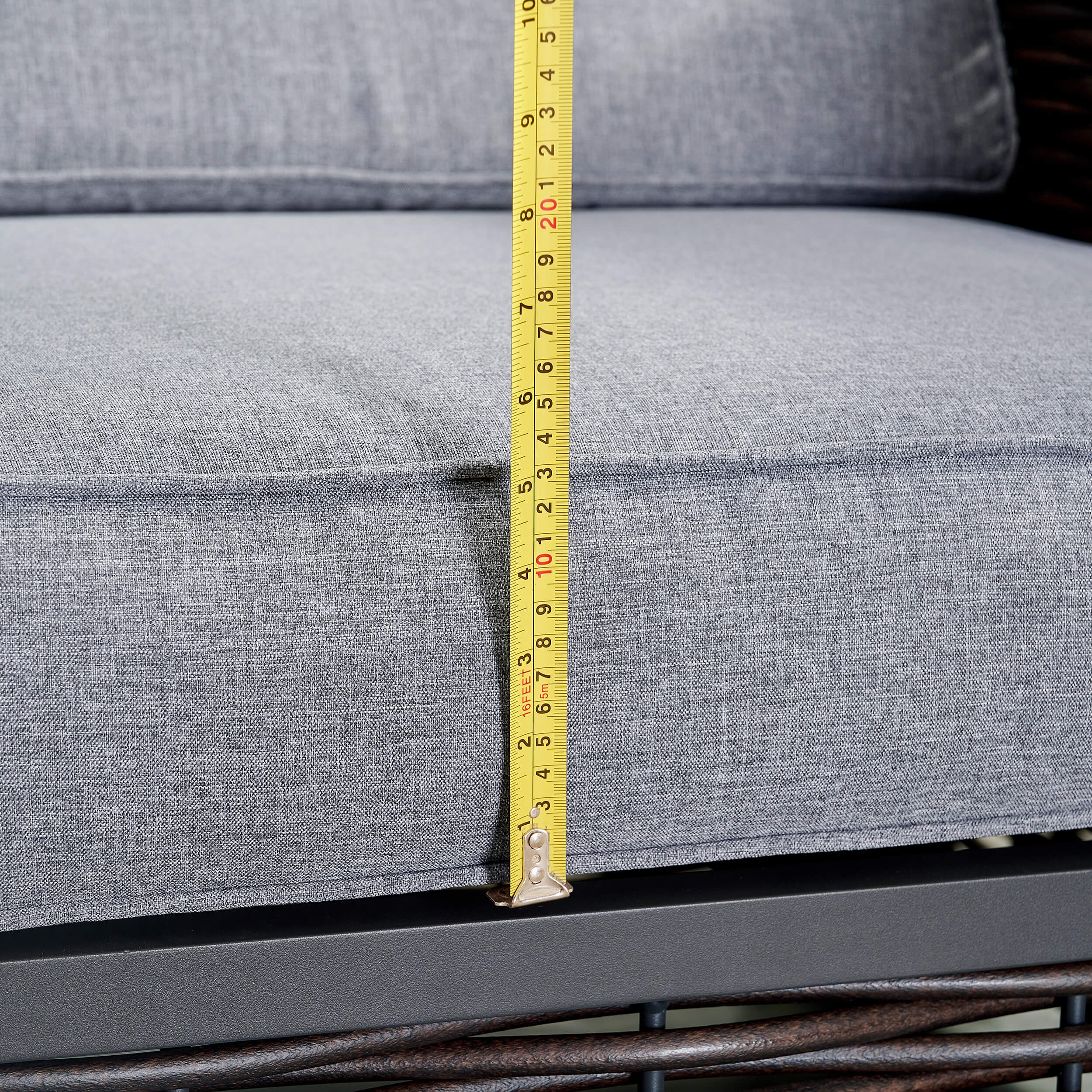 Gray outdoor chair cushion height measurement with yellow tape over black frame