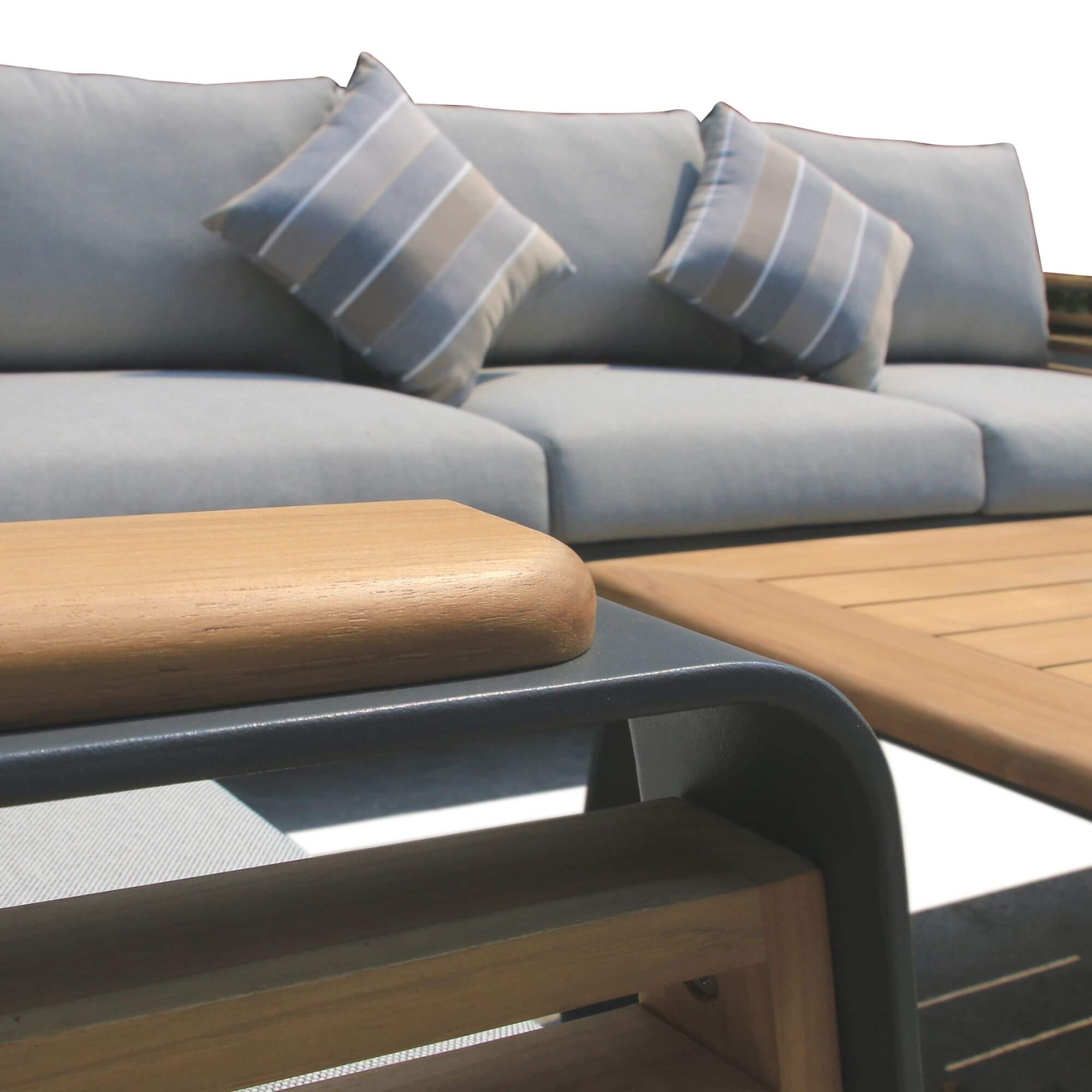 Outdoor patio coffee table corner with wood top and dark frame beside sofa cushions
