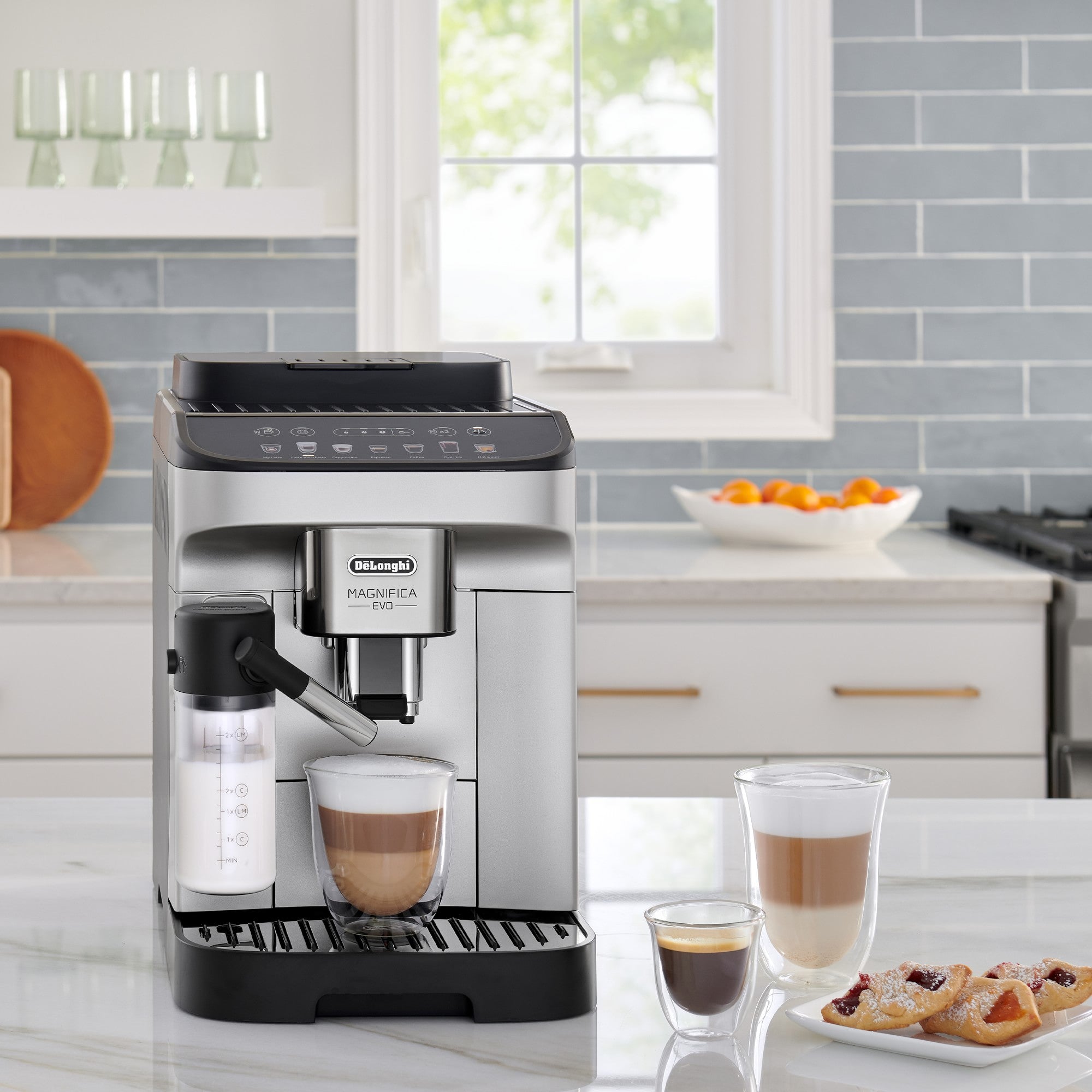 De'Longhi Magnifica Evo coffee machine serving cups on countertop with glass cups nearby